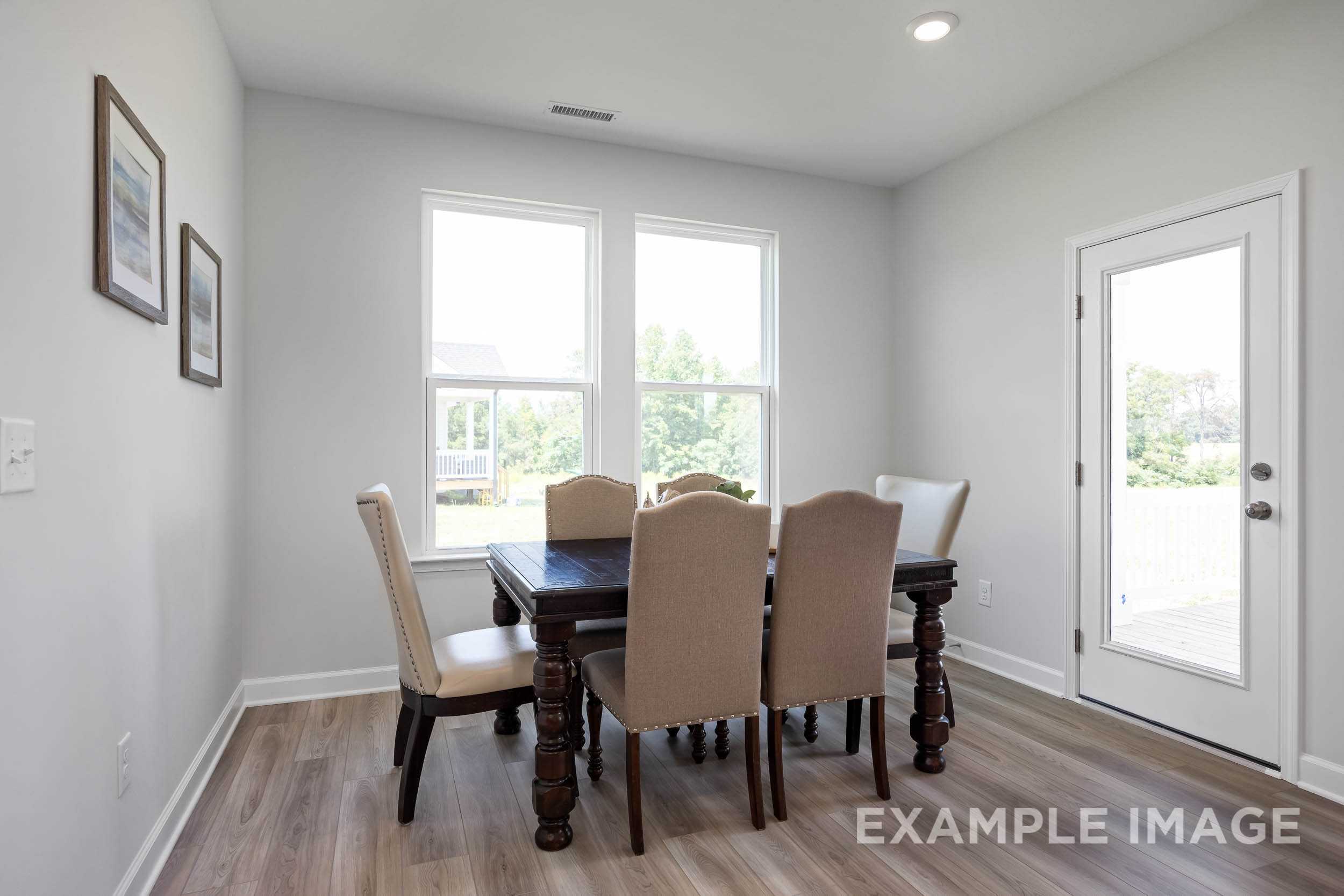 Spacious dining room in The Daphne C with wooden table, upholstered chairs, large windows, and light gray walls