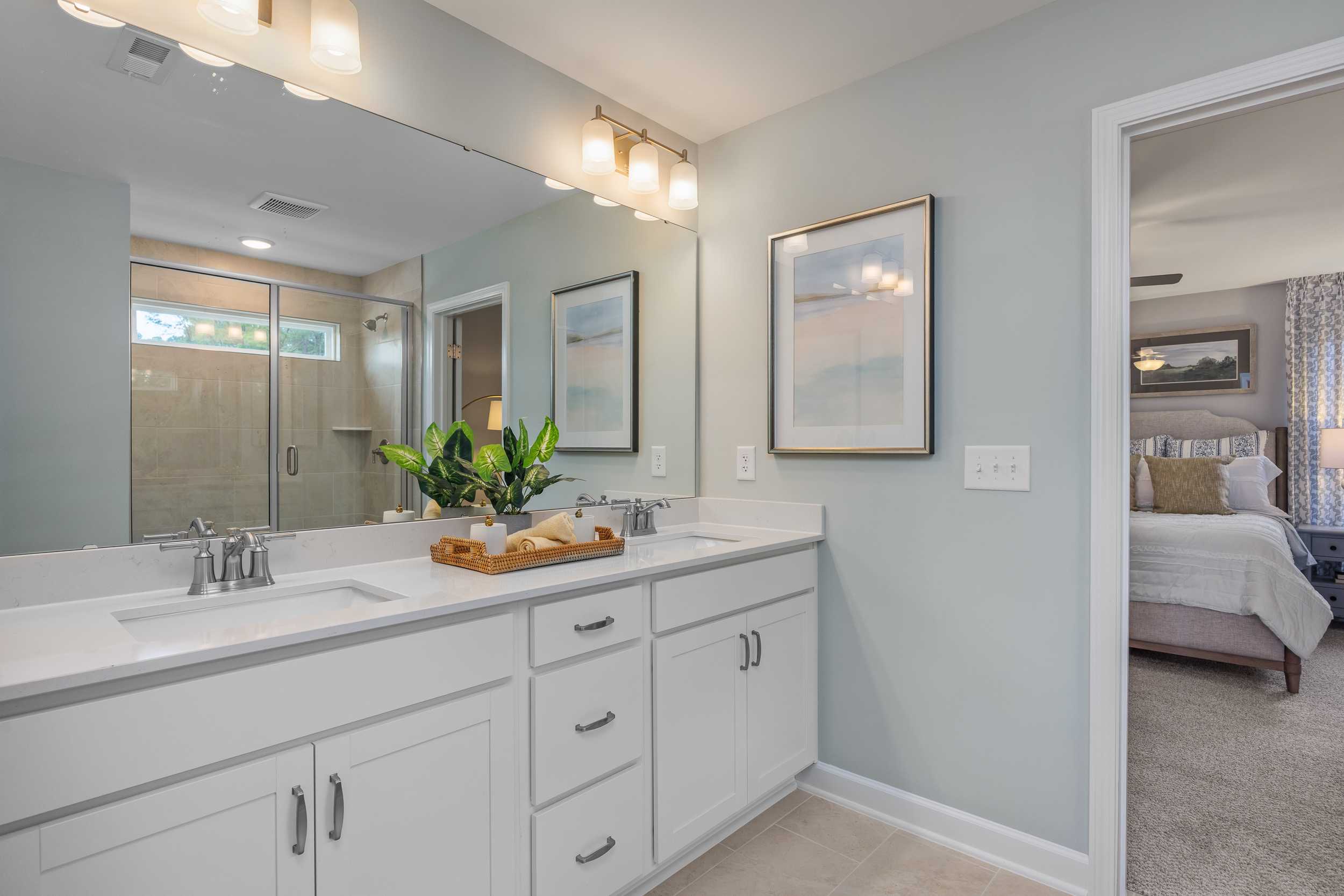 Spacious primary bathroom with double vanity, large mirror, and greenery at Retreat at North Main in Lillington NC