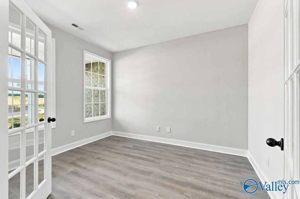 Bright empty room with gray walls and luxury vinyl plank flooring in Davidson Homes' The Rockford, Cain Park, Hartselle, AL
