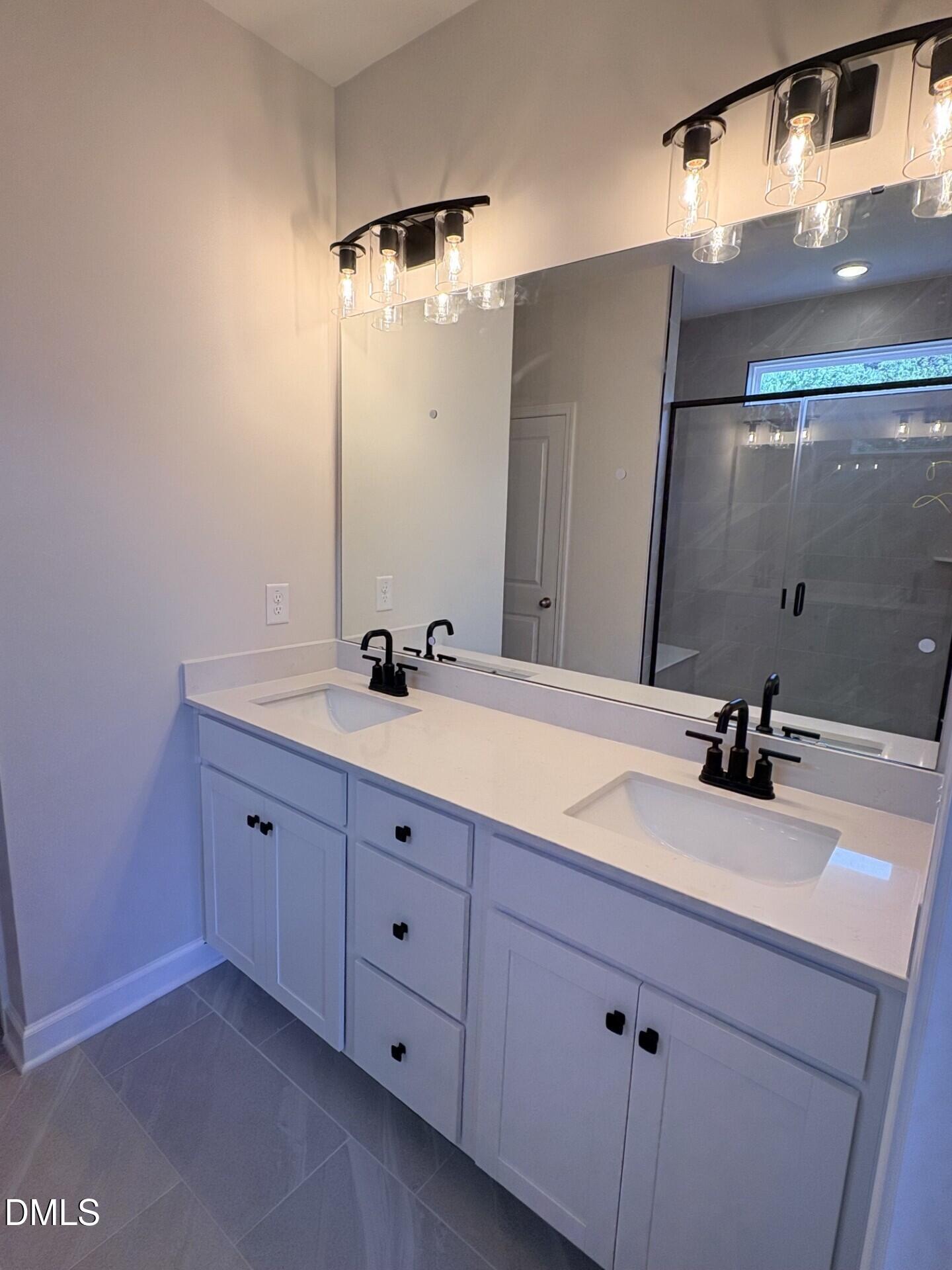 Modern double-vanity bathroom with white cabinets and black fixtures in The Ash C floor plan, Woodland Crossing, Zebulon.