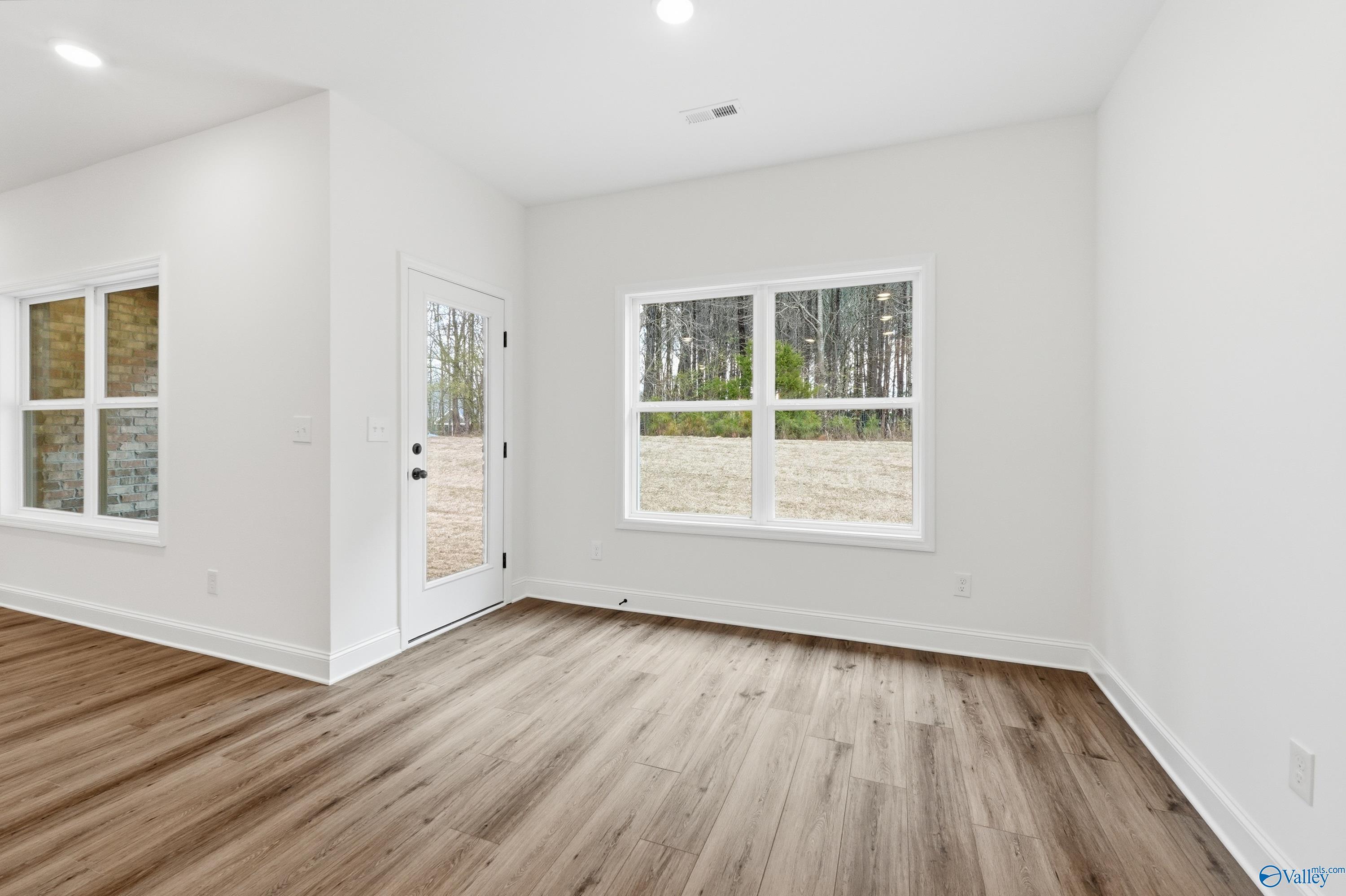 Bright dining area with wood-look flooring and backyard views in The Asheville C plan at The Highlands, Arab, Alabama.