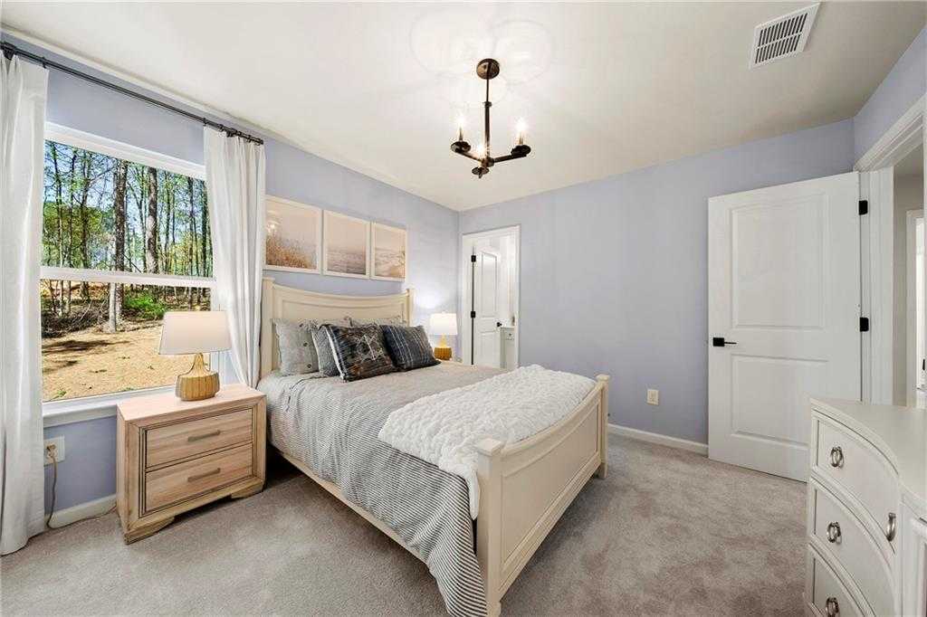 Light blue bedroom with large window overlooking wooded backyard, king bed, chandelier in Davidson Homes Hickory B, Riverwood, Dallas, GA