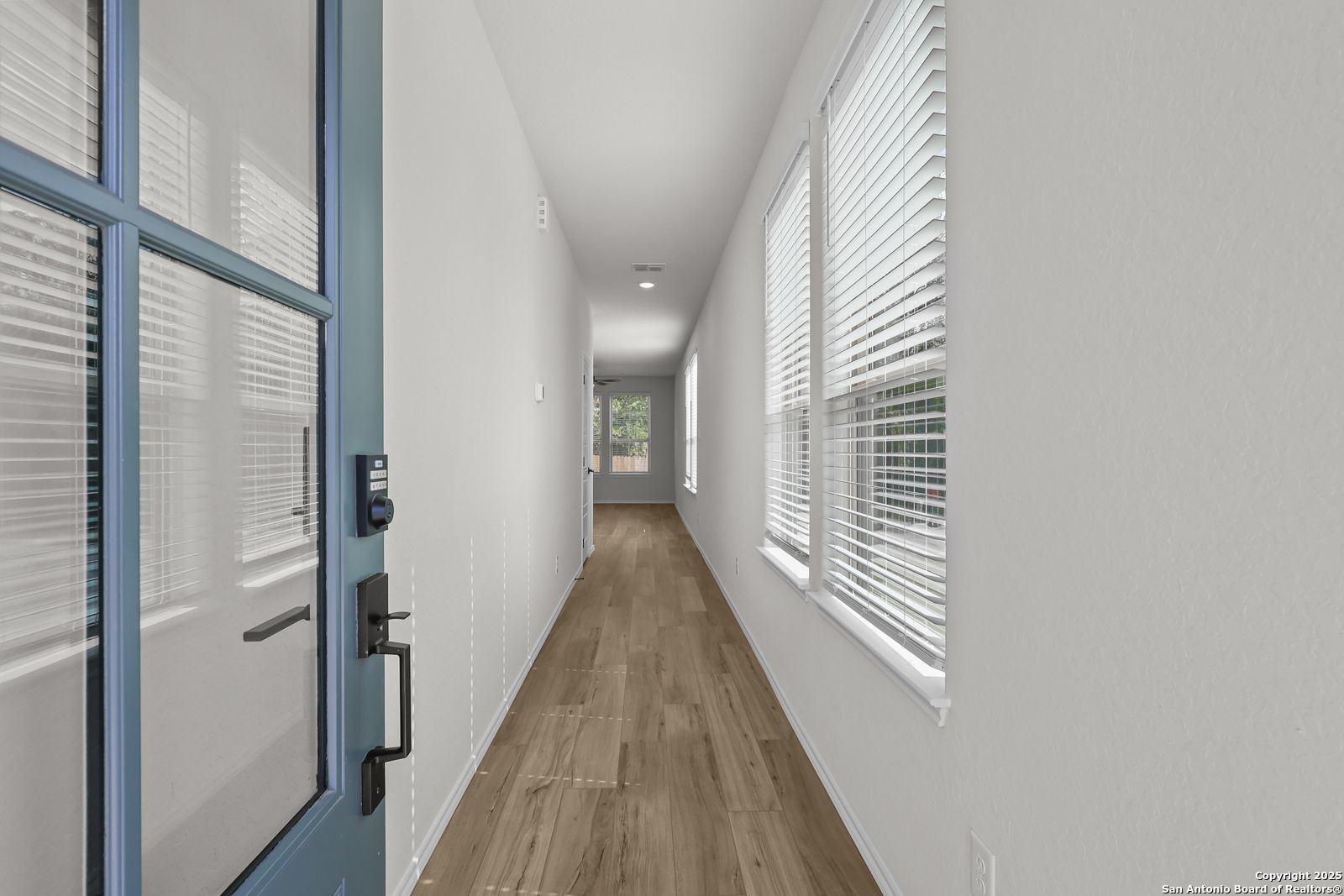 Bright entry hallway with light wood floors and window blinds in Davidson Homes The Florence C, San Antonio
