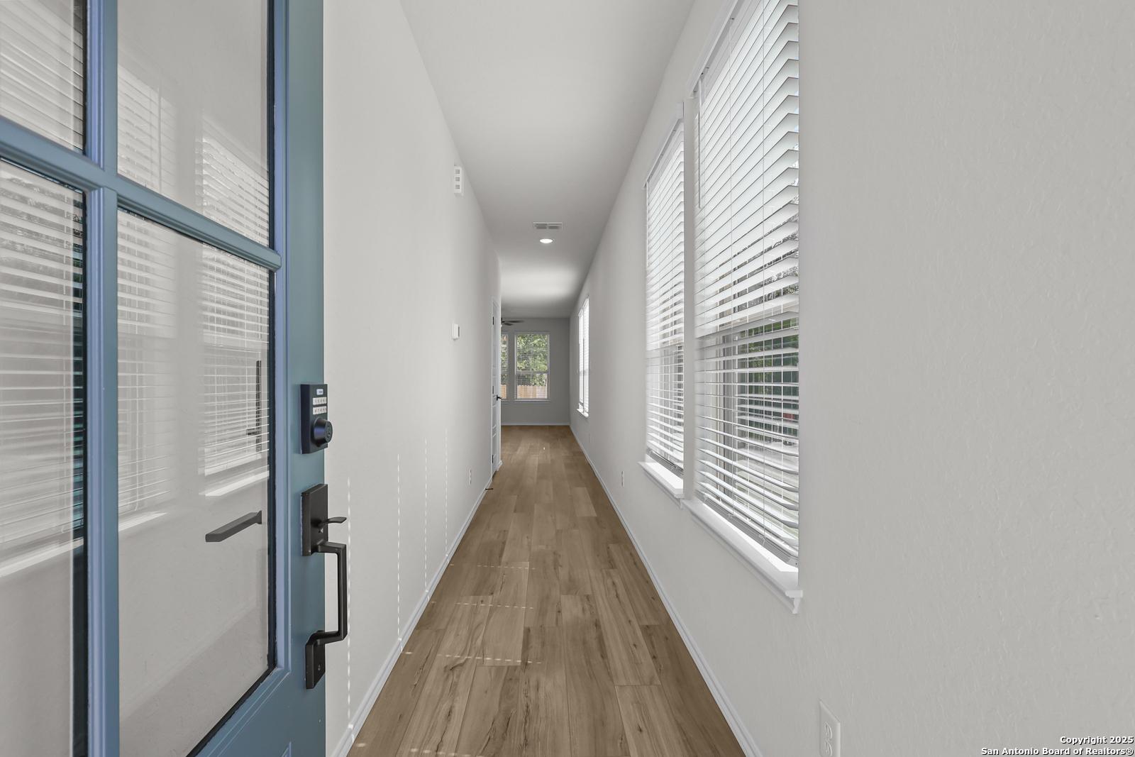 Bright entry hallway with light wood floors and window blinds in Davidson Homes The Florence C, San Antonio