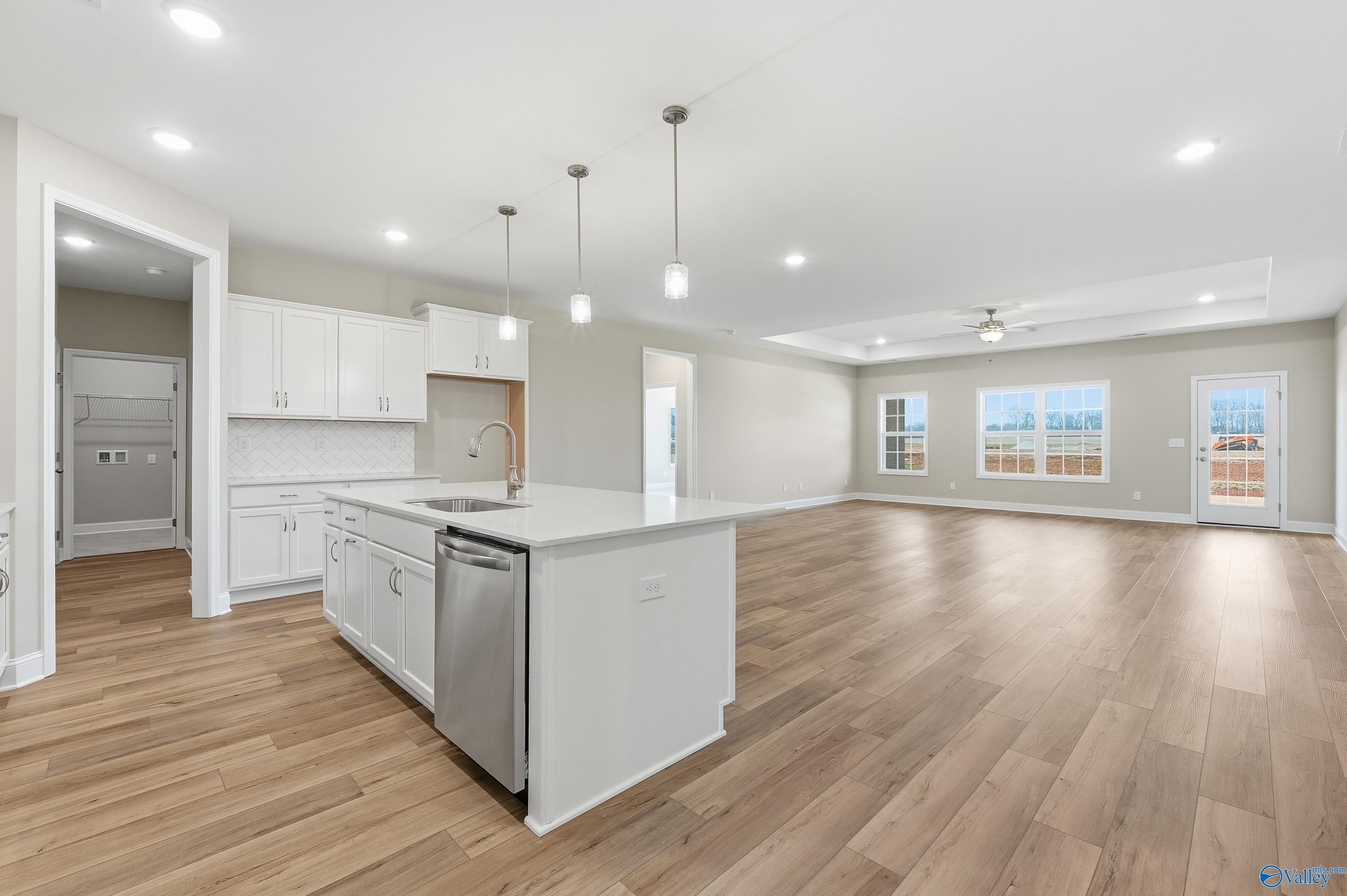 Spacious open-concept kitchen with white island, stainless dishwasher, and hardwood floors in The Lanier home, Meridianville, AL