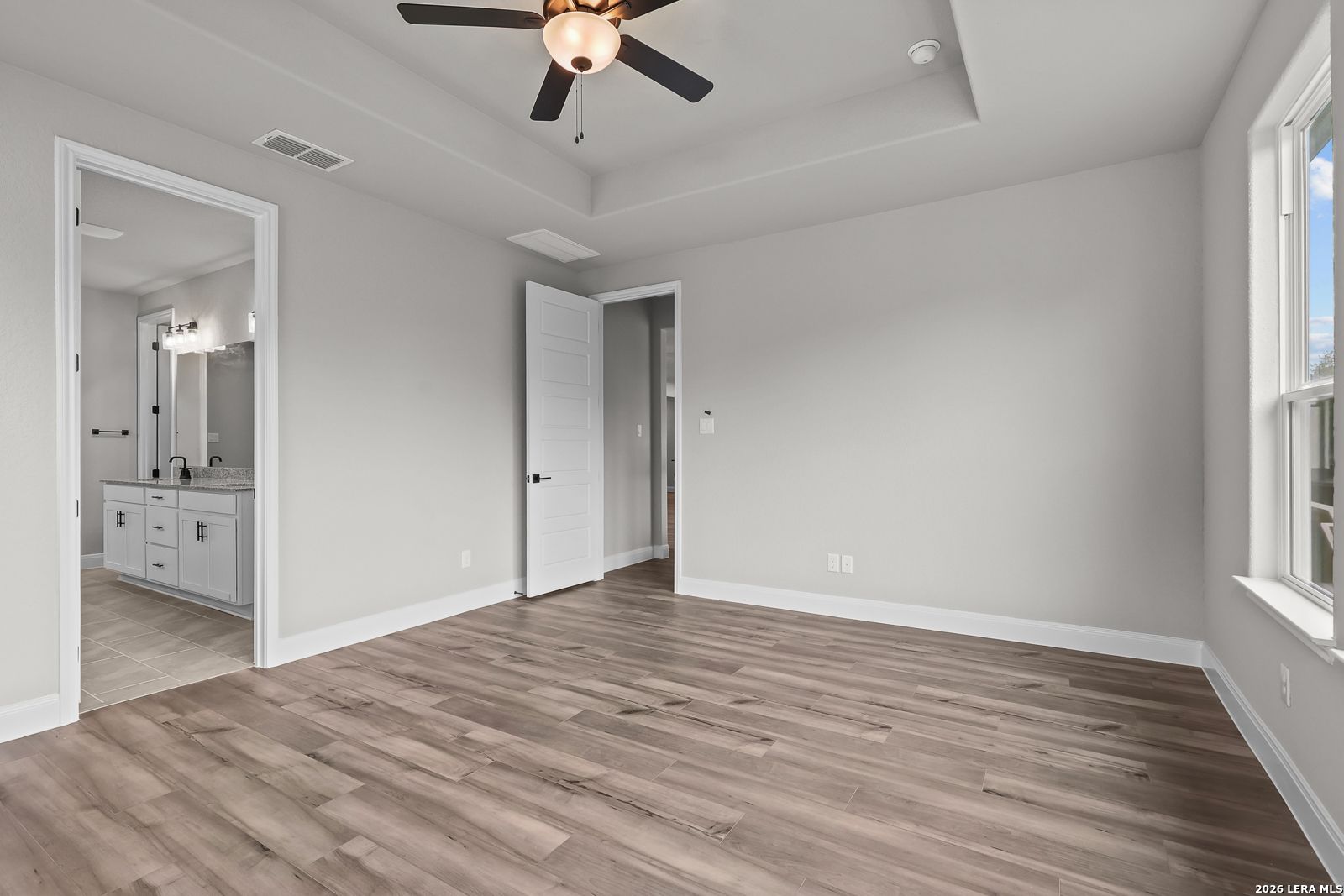 Spacious master bedroom with ceiling fan, hardwood floors, and en-suite bath in Davidson Homes The Belmont H, Castroville, Texas