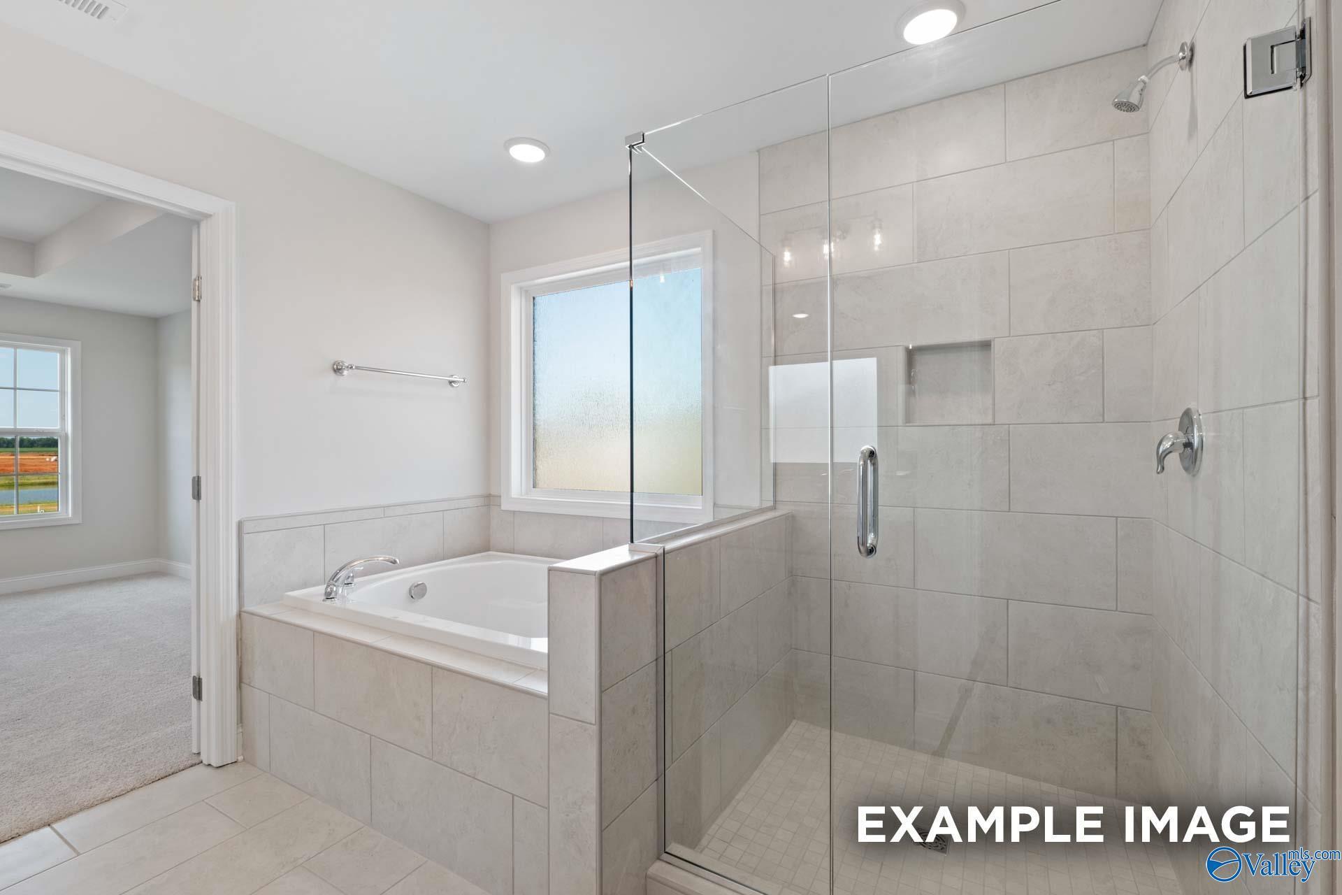 Luxurious master bathroom with soaking tub, glass shower, and tiled accents in Davidson Homes The Madison A, Toney, Alabama