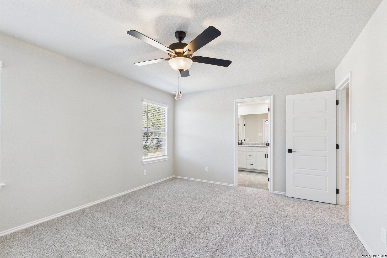 Spacious secondary bedroom with gray walls, carpet floor, ceiling fan, and en-suite bath in Davidson Homes The Charlotte A, San Antonio
