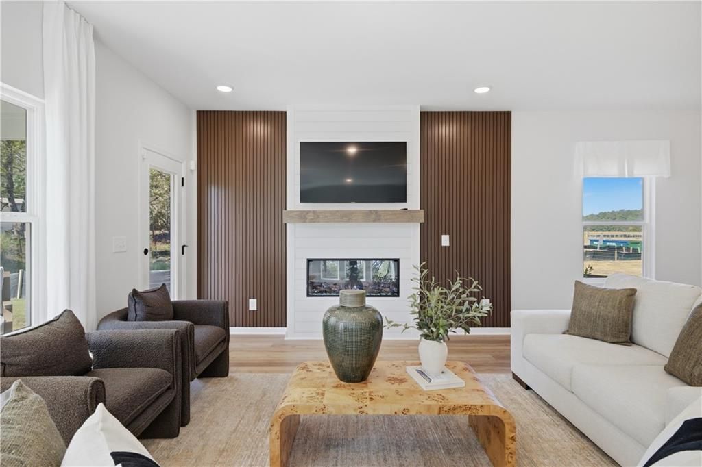 Bright living room with linear fireplace, wood accent walls, and mounted TV in Davidson Homes The Sinclair B, Cartersville, GA