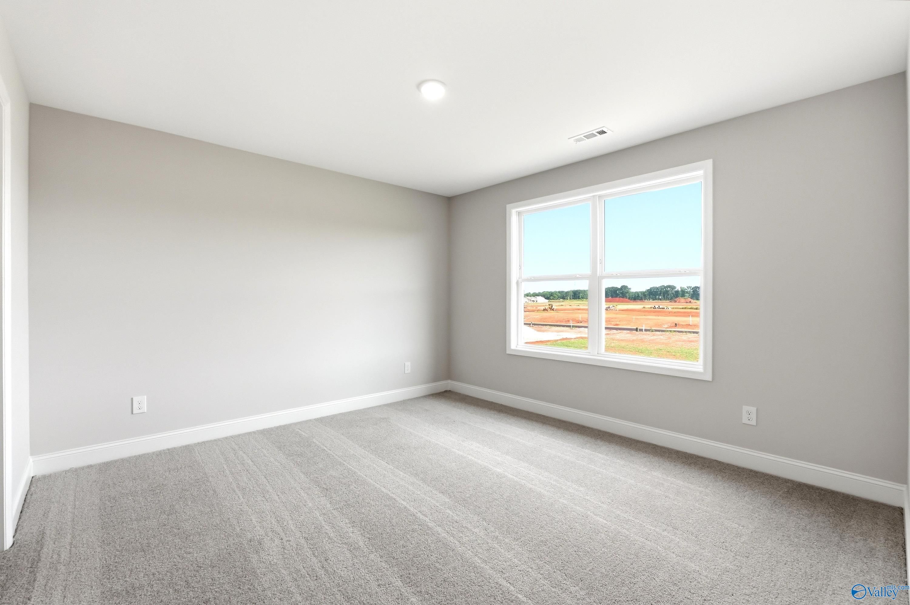 Bright, spacious secondary bedroom with neutral carpet and large window in The Shelby A floor plan, Hazel Green, Alabama.