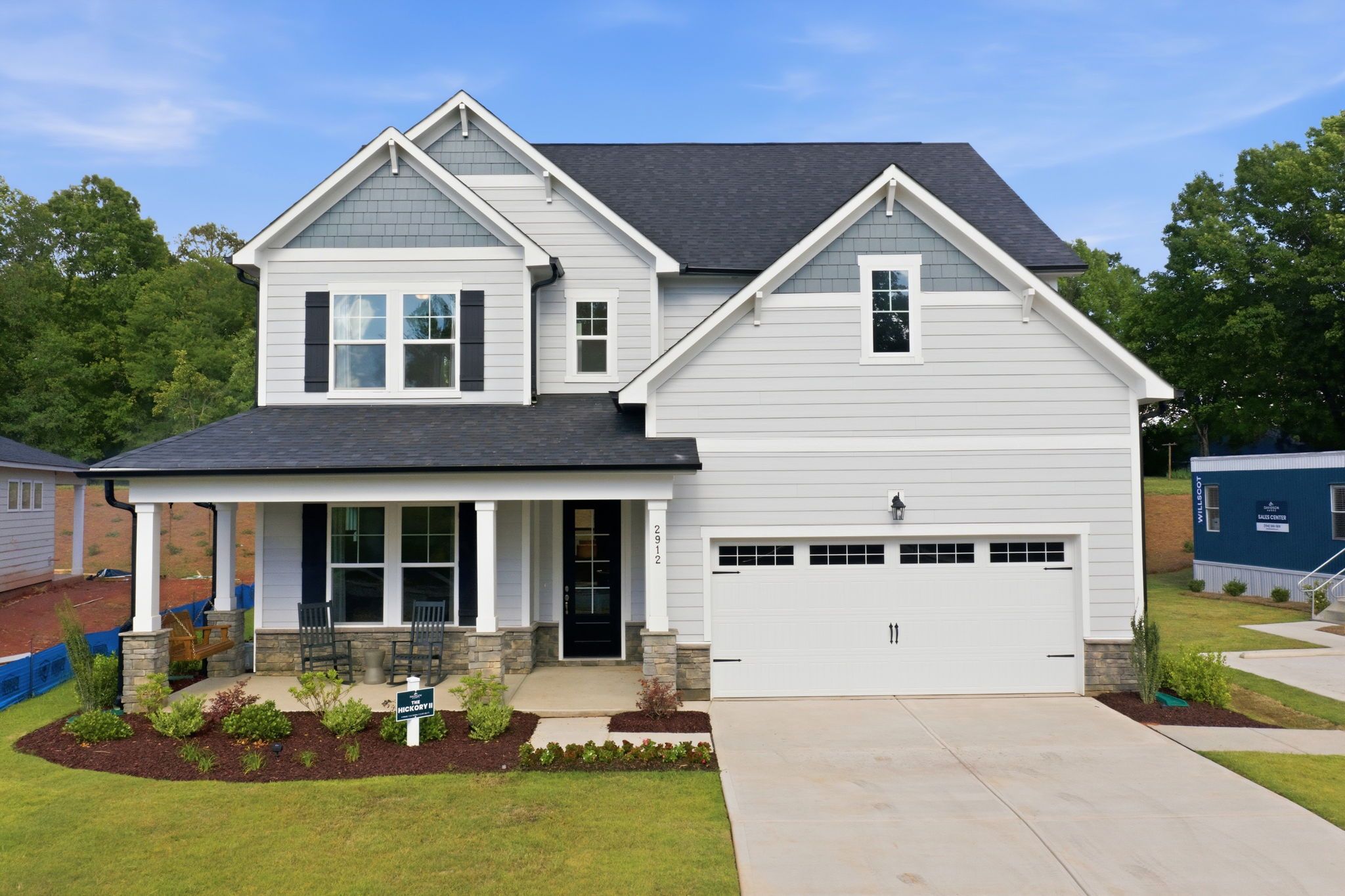 Modern craftsman-style home exterior at Enclave at Belmont in Belmont NC with covered porch, two-car garage, and lush landscaping
