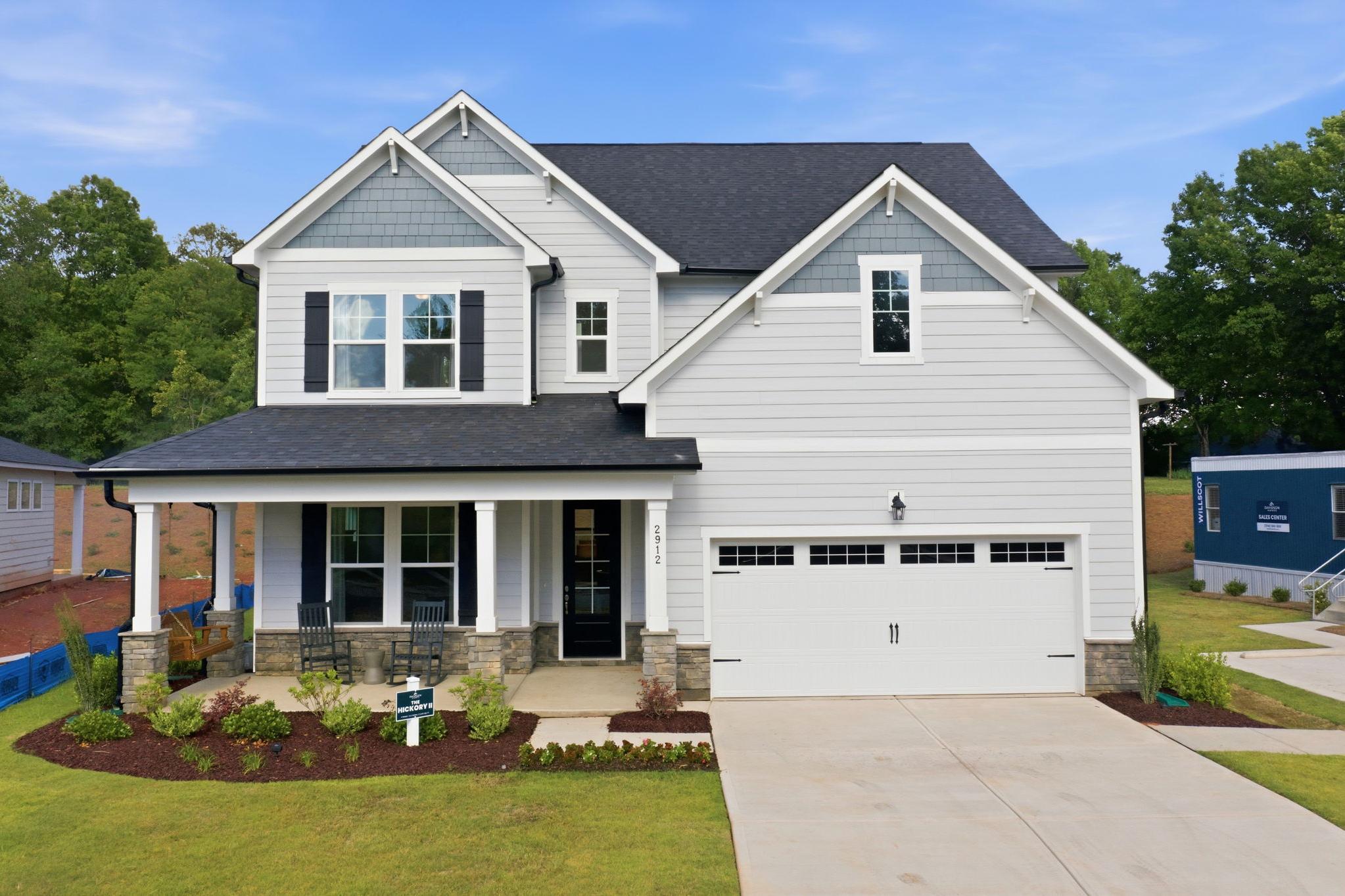 Modern craftsman-style home exterior at Enclave at Belmont in Belmont NC with covered porch, two-car garage, and lush landscaping