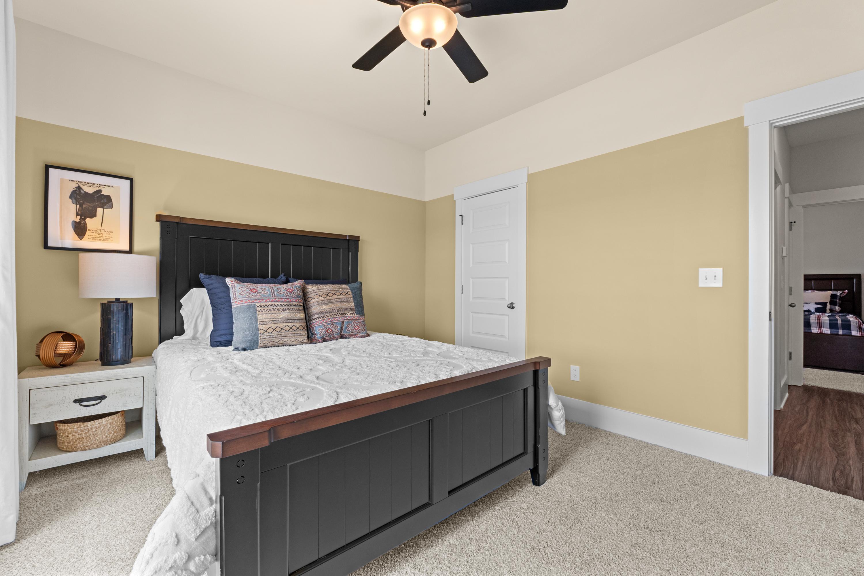 Cozy bedroom at Ivy Hills in Toney Alabama by Davidson Homes with dark wood bed frame beige walls and ceiling fan