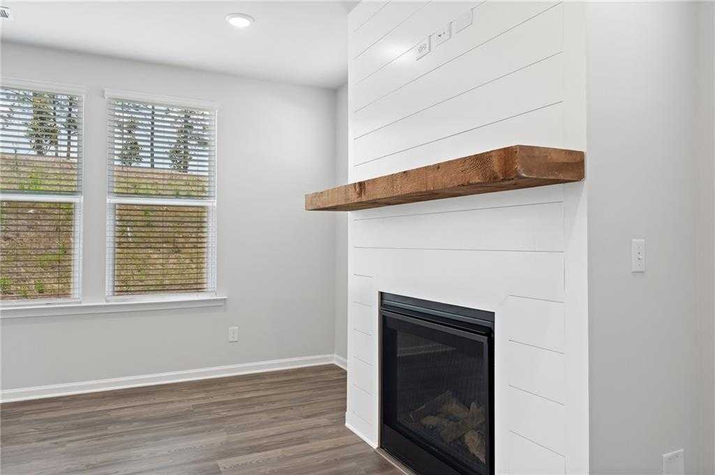 Cozy white shiplap fireplace with rustic wooden mantel and gas logs in living room of 5-bedroom Davidson Homes The Hickory B, Winder, Georgia