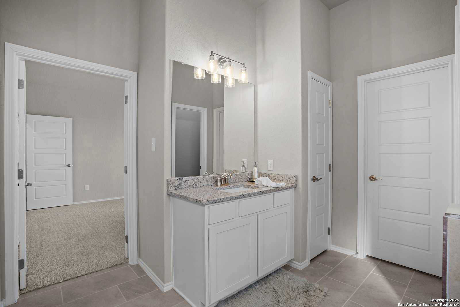Modern master bath with granite double vanity, white cabinets, and subway tile in Davidson Homes Collin B, Seguin, Texas