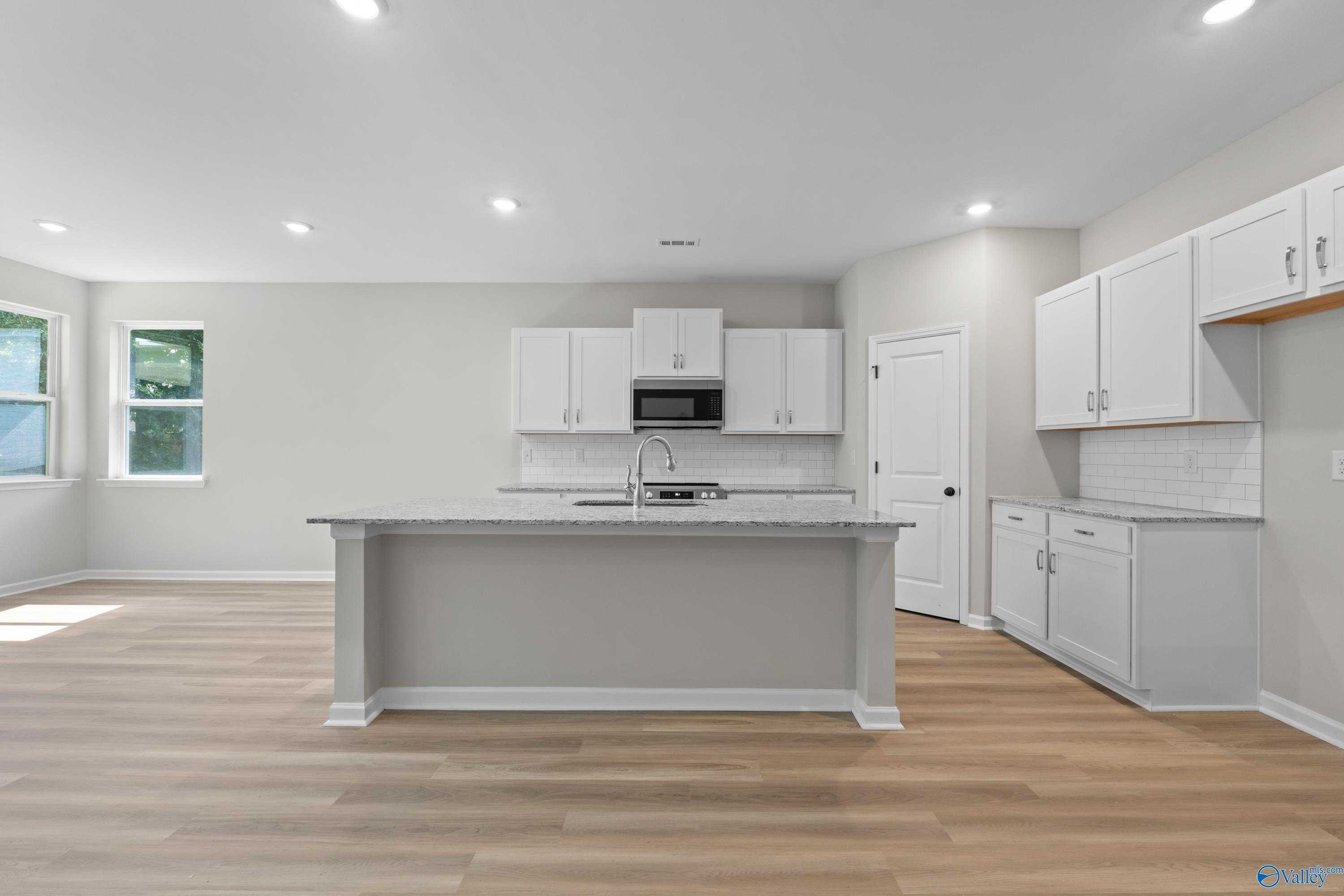 Bright open kitchen with white cabinets, granite island, stainless appliances in Davidson Homes The Phoenix, Fayetteville TN