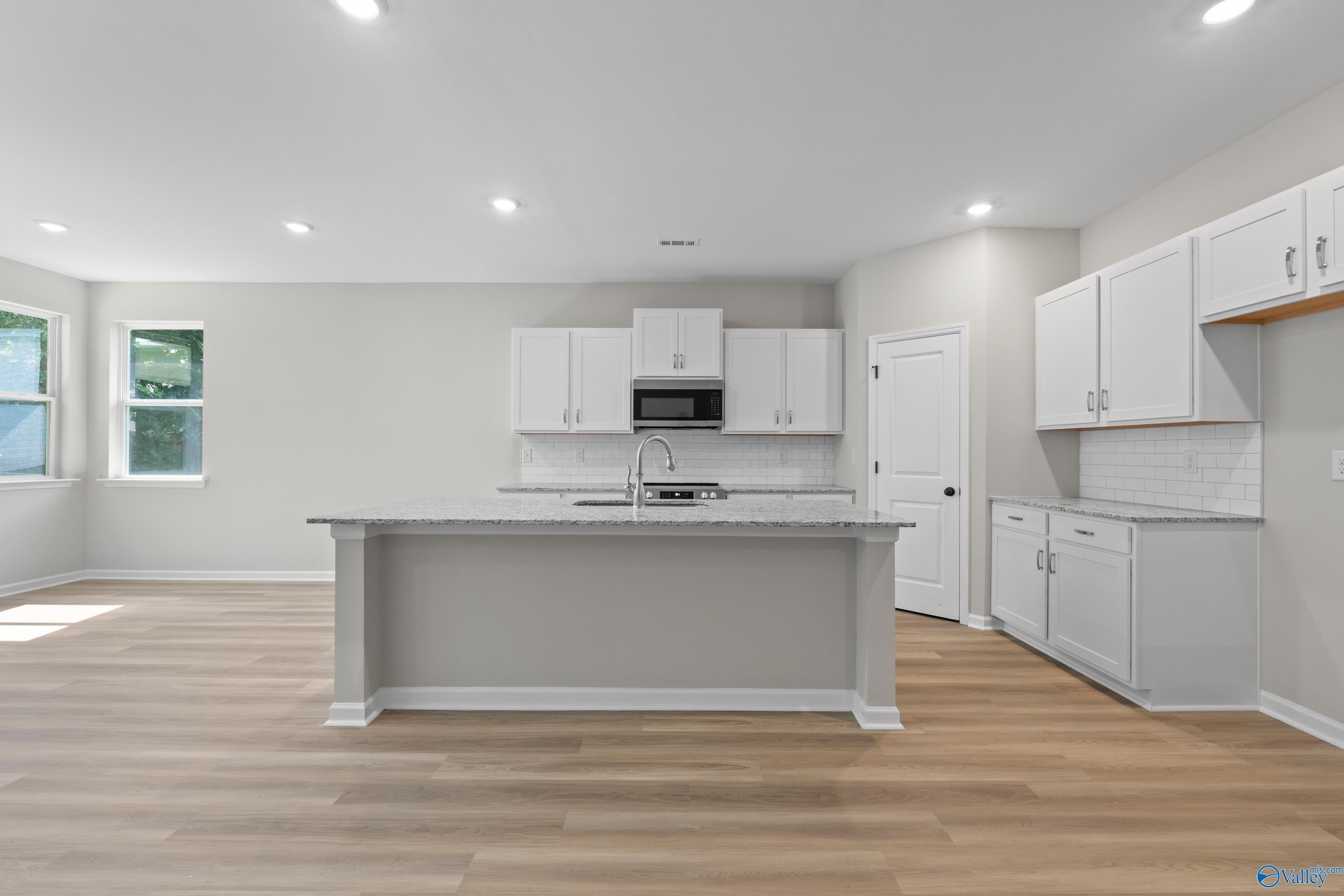 Modern white kitchen with granite island, stainless appliances, and open layout in Davidson Homes The Phoenix, Fayetteville, TN
