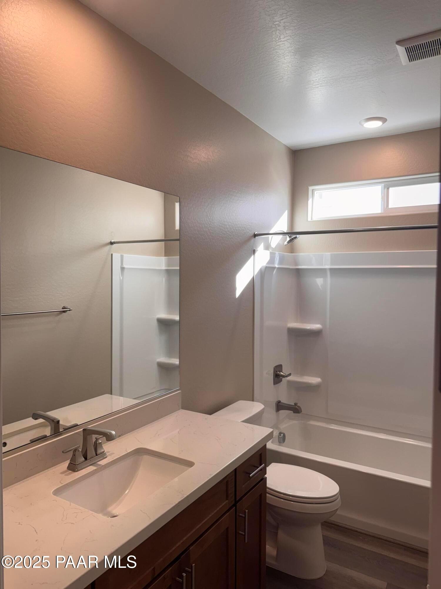 Modern bathroom featuring quartz vanity, tub-shower combo, and wood-look flooring in Davidson Homes The Sunrise II A, Prescott, AZ