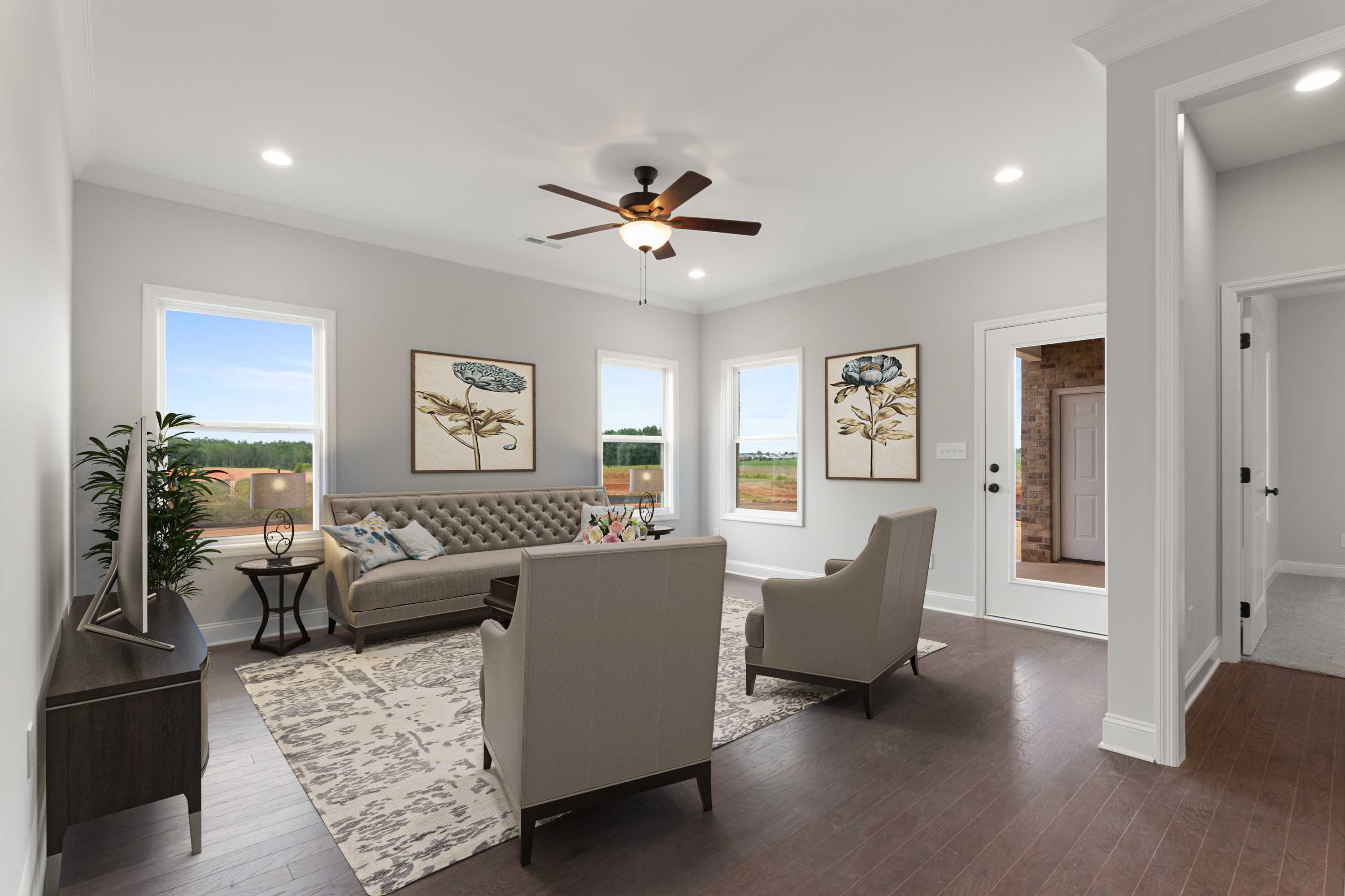 Spacious living room at The Villas at Barnett's Crossing in Madison Alabama with beige sofa armchairs hardwood floors and large windows