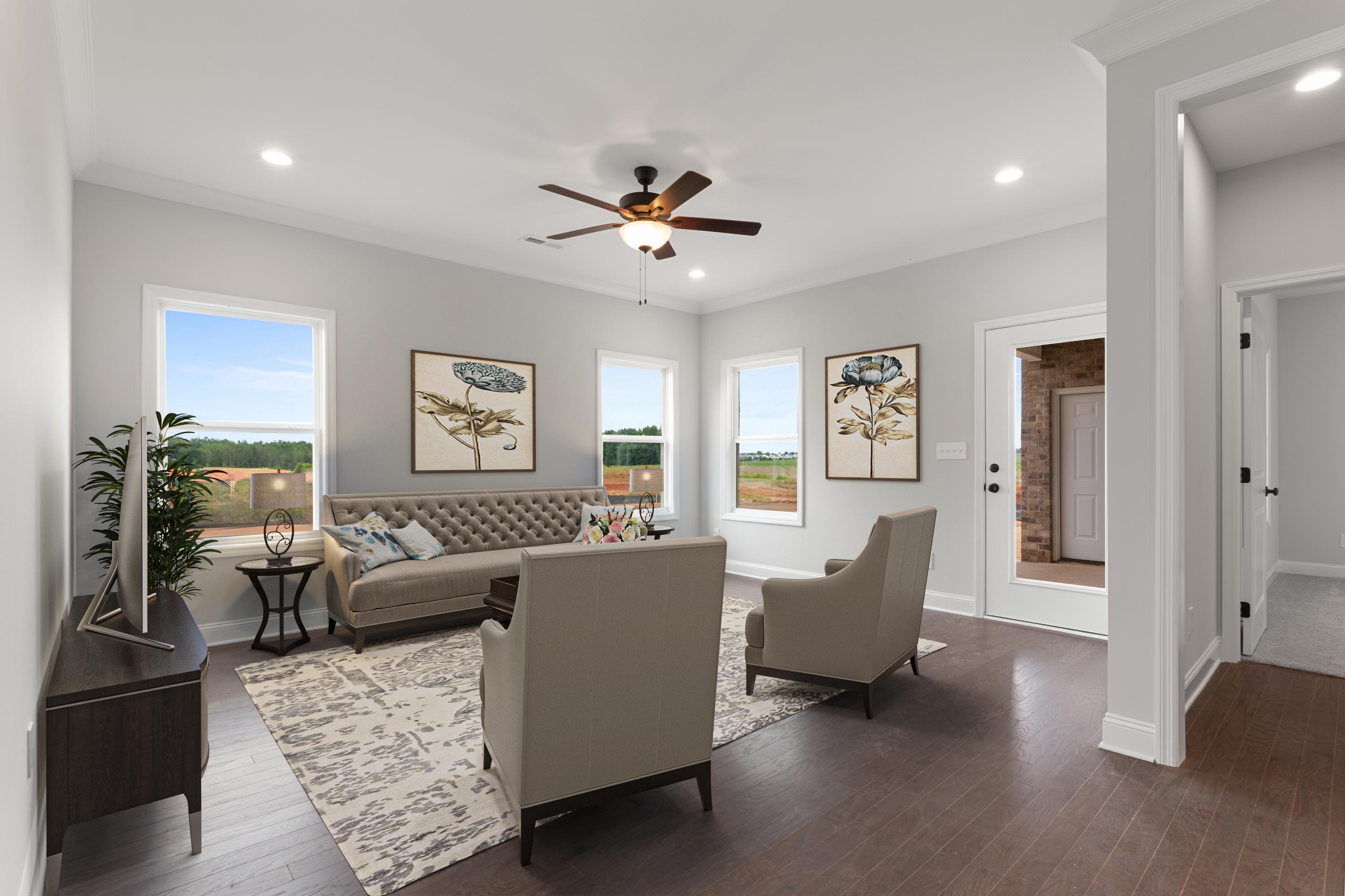 Spacious living room at The Villas at Barnett's Crossing in Madison Alabama with beige sofa armchairs hardwood floors and large windows