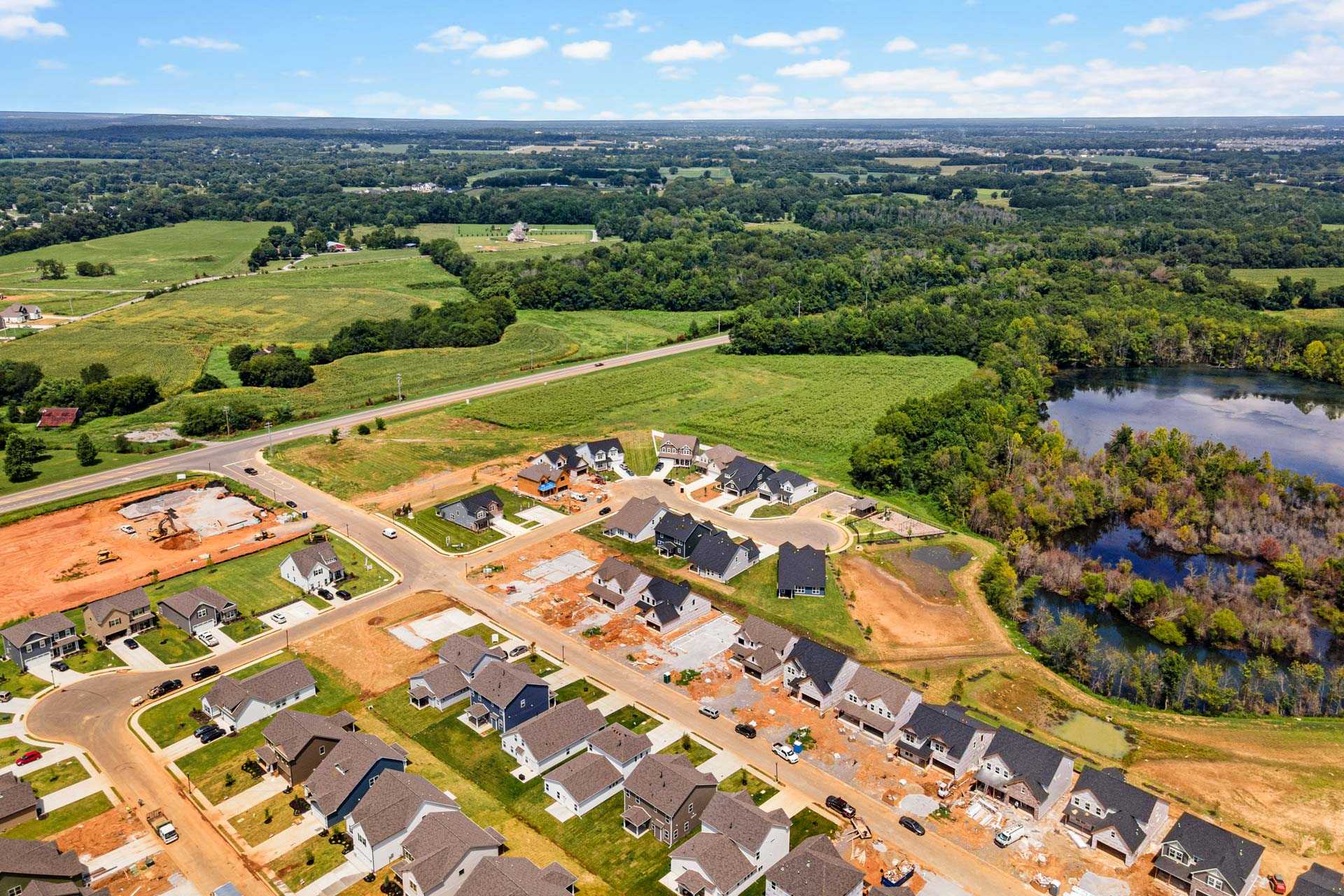 Aerial view of Salem Landing new homes in Murfreesboro Tennessee by Davidson Homes amid green fields, woods, and pond