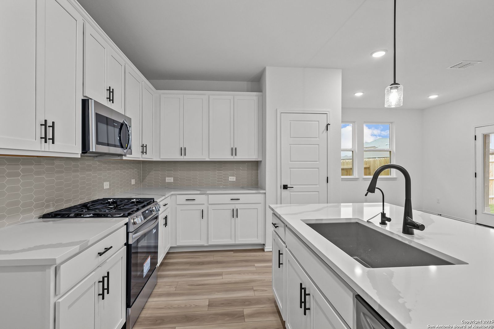 Modern white kitchen with quartz counters, stainless appliances, subway tile backsplash in The Daphne J, Davidson Homes, Converse, Texas