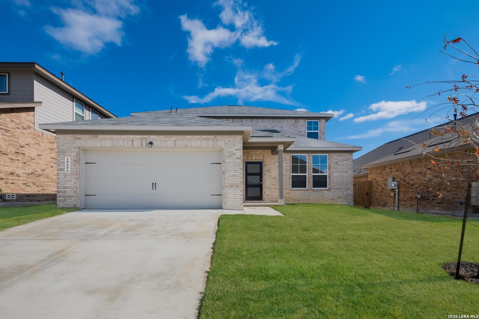 Two-story brick 4-bedroom home with 2-car garage, driveway, and green lawn in Bricewood, San Antonio, Texas