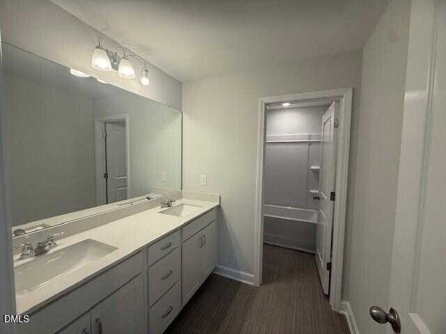 Modern master bathroom featuring double vanity, white cabinets, large mirror, and adjacent soaking tub in Davidson Homes The Preston C, Lillington, NC