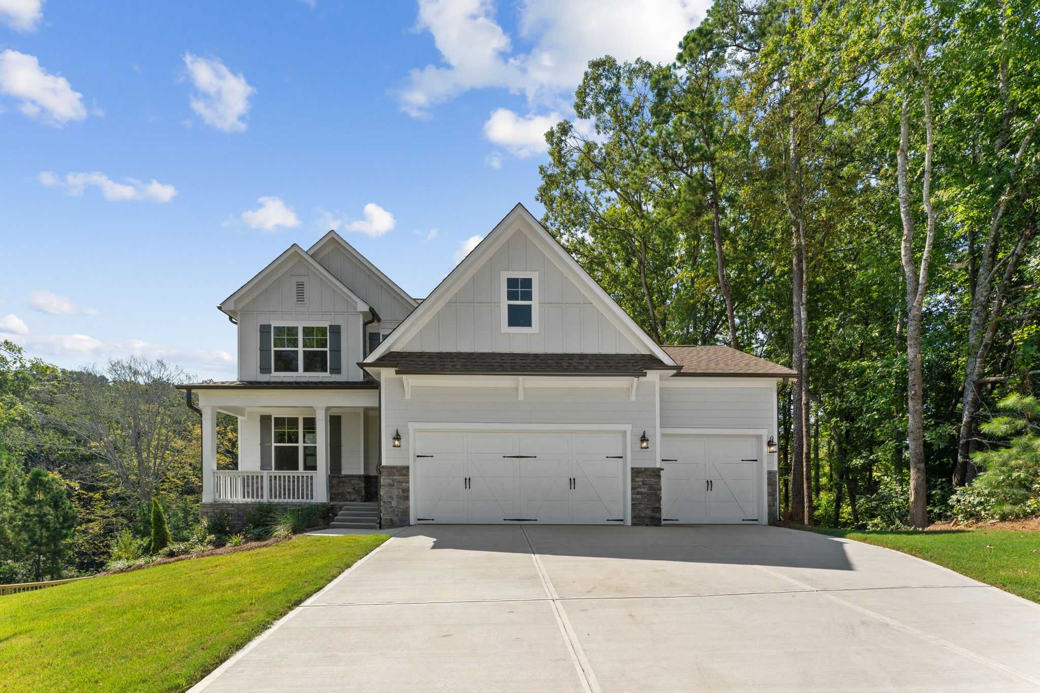 Modern farmhouse home exterior at Riverwood in Dallas GA with covered porch, two-car garage, and lush landscaping
