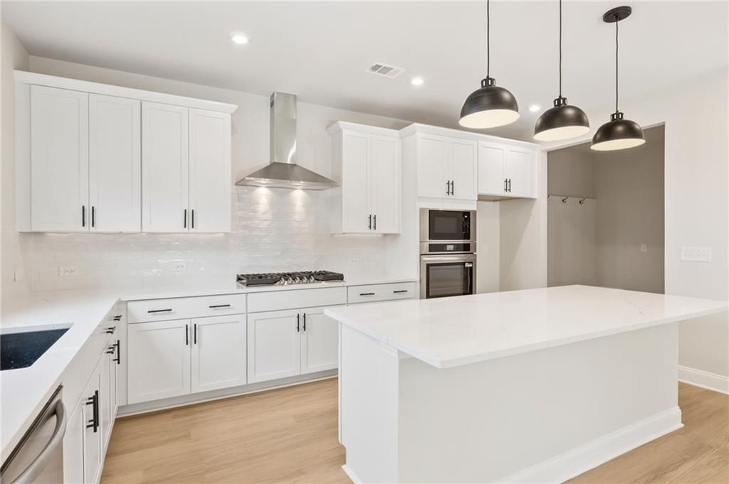 Modern white kitchen island with stainless steel appliances and subway tile backsplash in Davidson Homes The Hickory B, Buford, GA