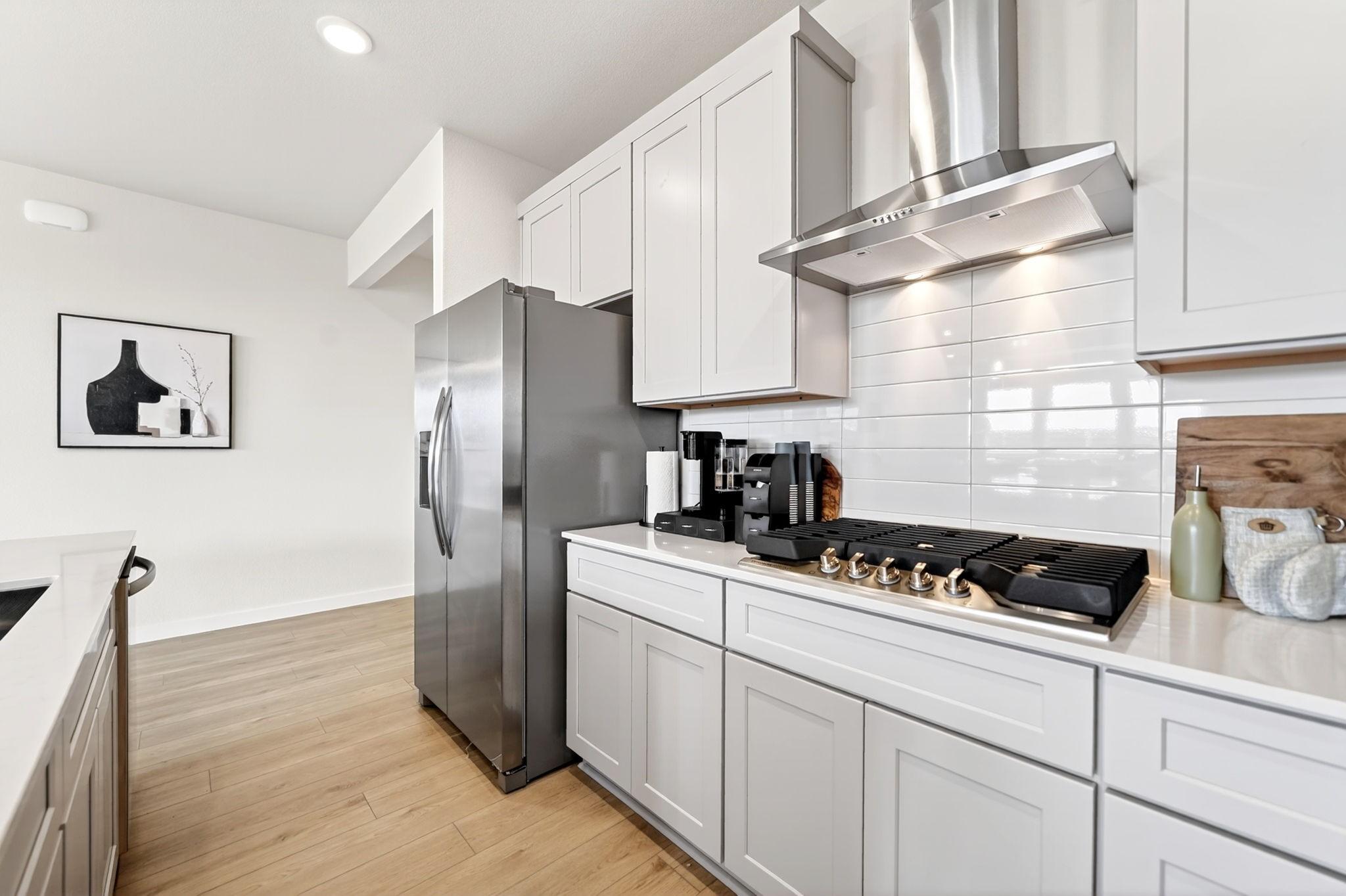 Modern kitchen with stainless appliances, white cabinets, and gas cooktop in The Laurel O floor plan, Anna, Texas.