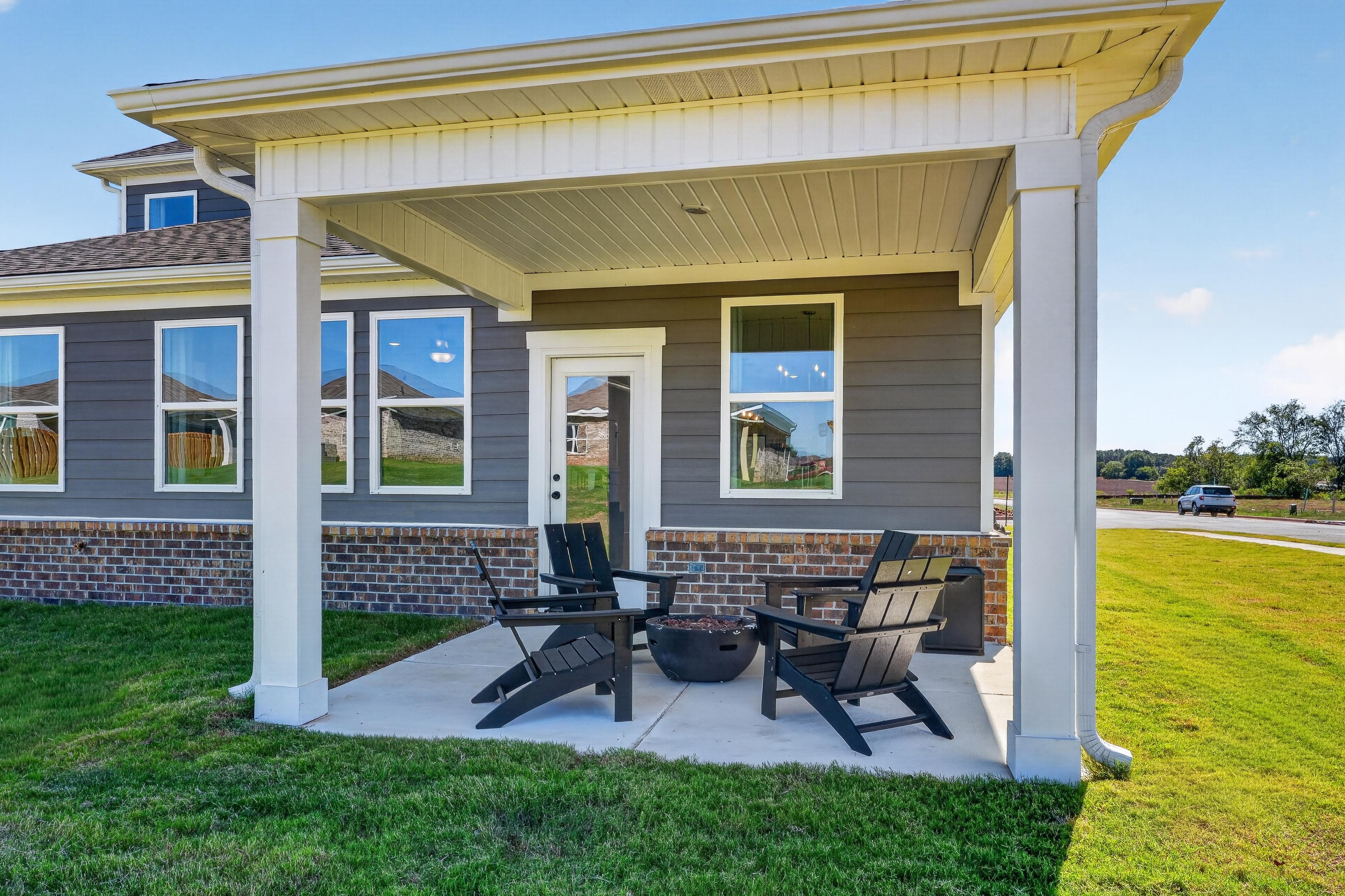 Covered back patio with fire pit and Adirondack chairs at Evergreen Mill new homes by Davidson Homes in Madison, Alabama