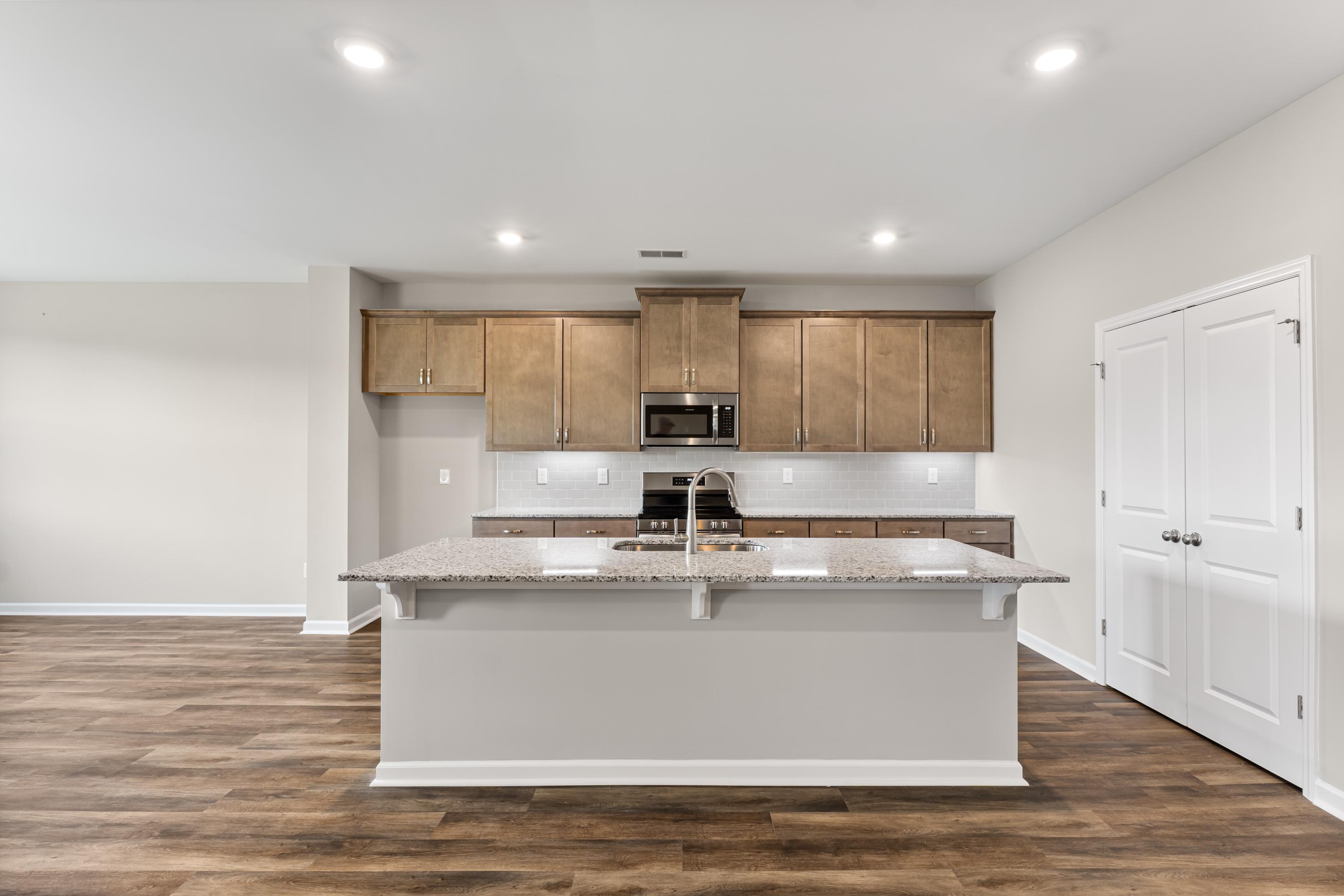 Spacious kitchen in The Haven E with large granite island, shaker wood cabinets, and stainless appliances