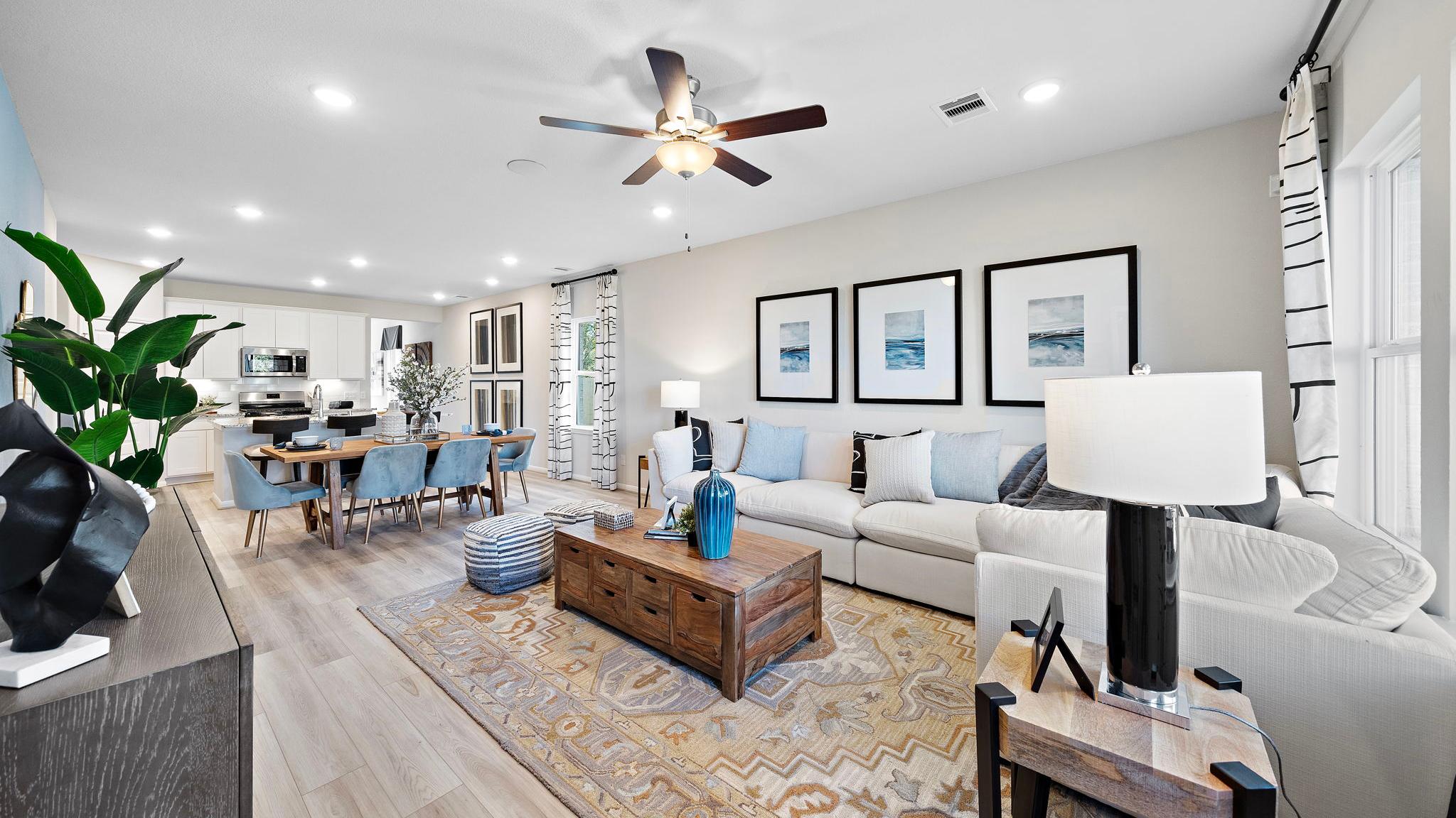 Open-concept living and dining room at Lakes at Black Oak in Magnolia Texas with hardwood floors, white sofa, and ceiling fans