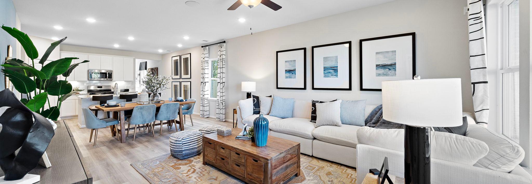 Open-concept living and dining room at Lakes at Black Oak in Magnolia Texas with hardwood floors, white sofa, and ceiling fans