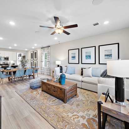 Open-concept living and dining room at Lakes at Black Oak in Magnolia Texas with hardwood floors, white sofa, and ceiling fans