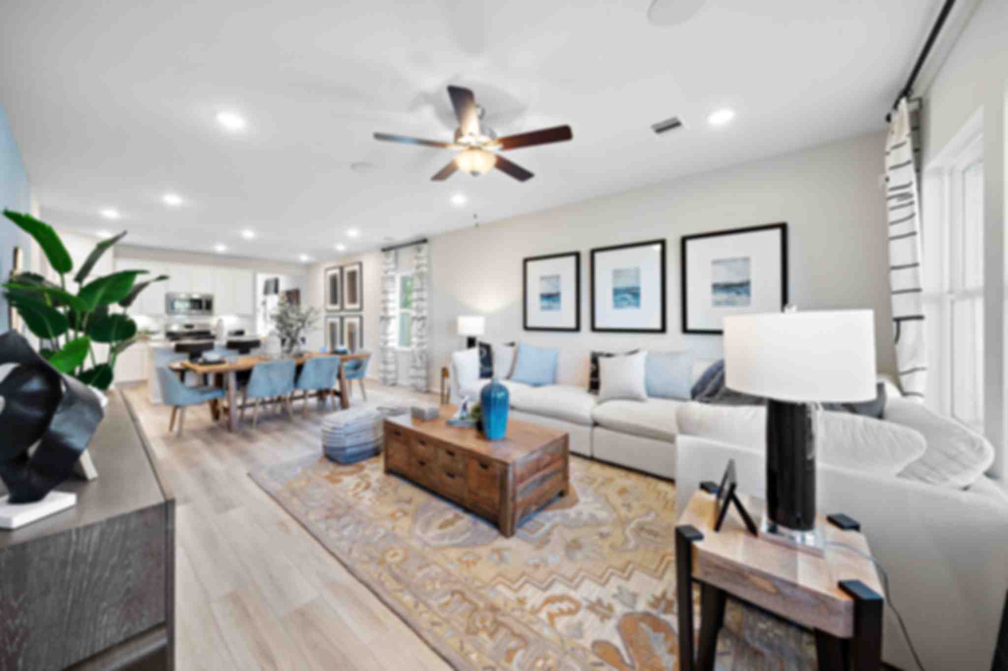 Open-concept living and dining room at Lakes at Black Oak in Magnolia Texas with hardwood floors, white sofa, and ceiling fans