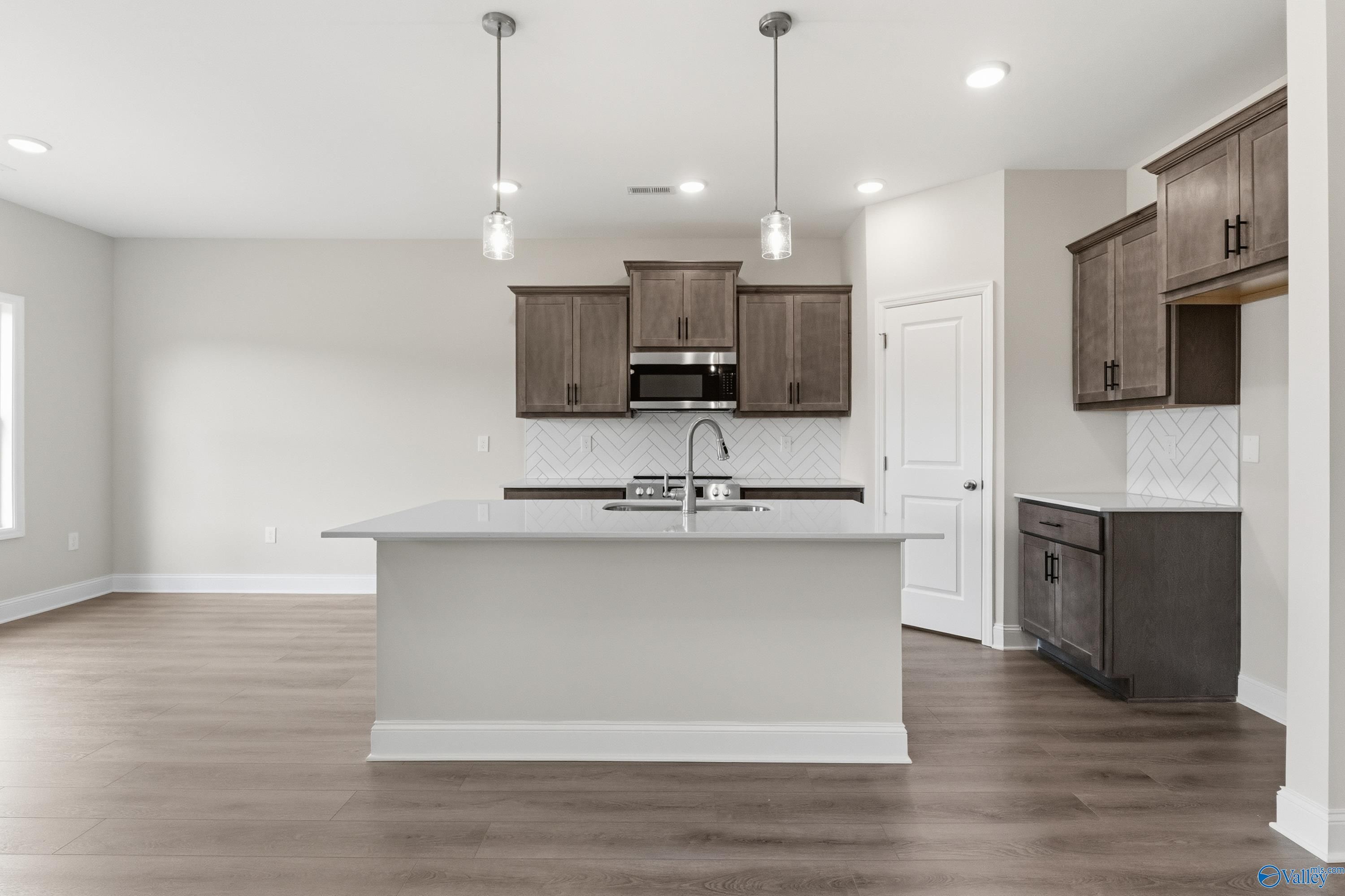 Modern kitchen featuring white quartz island, espresso shaker cabinets, and stainless sink in Davidson Homes The Asheville C, Huntsville, AL