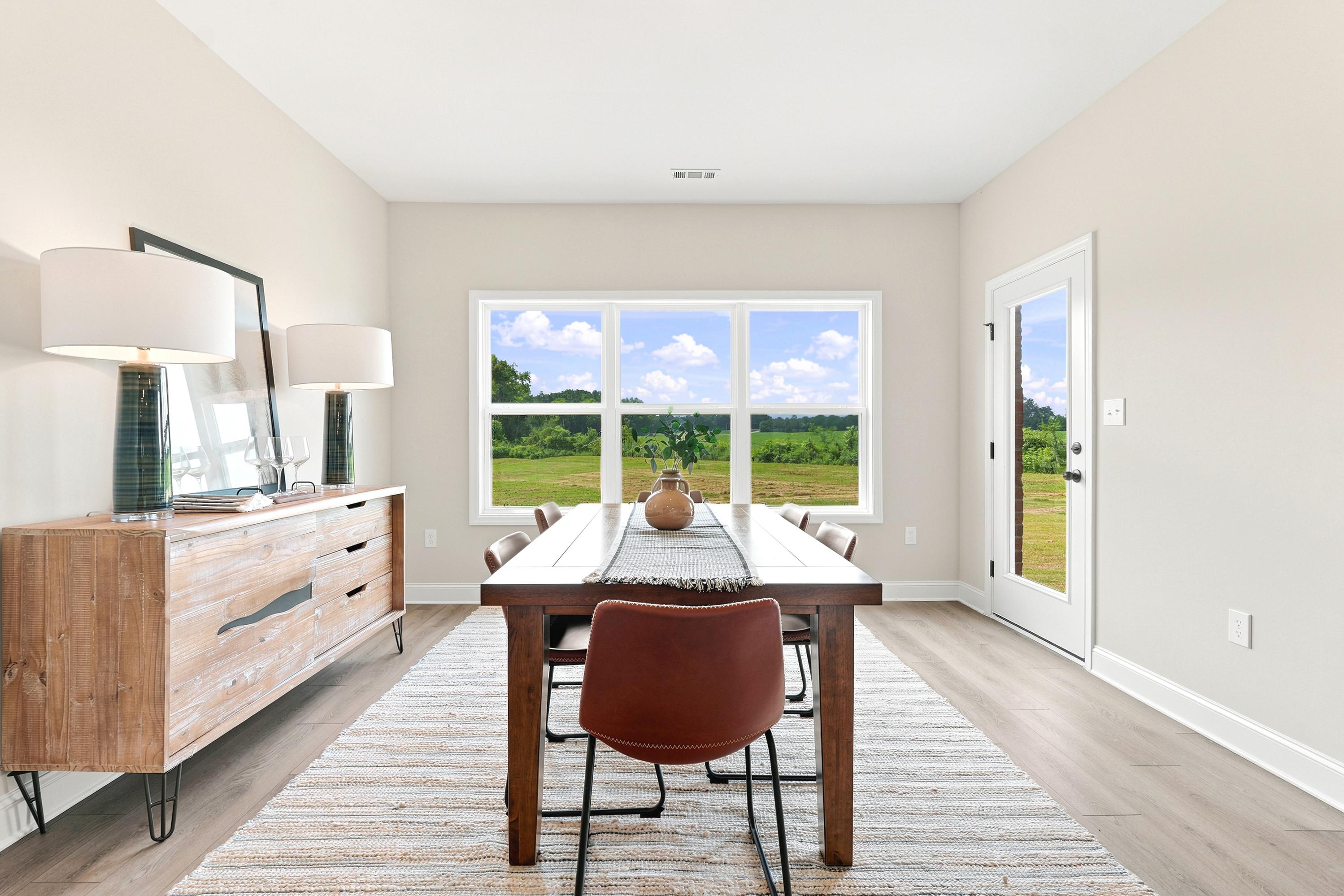 Modern dining room at Riverton Preserve in Huntsville, AL by Davidson Homes featuring a wood table and rustic sideboard.