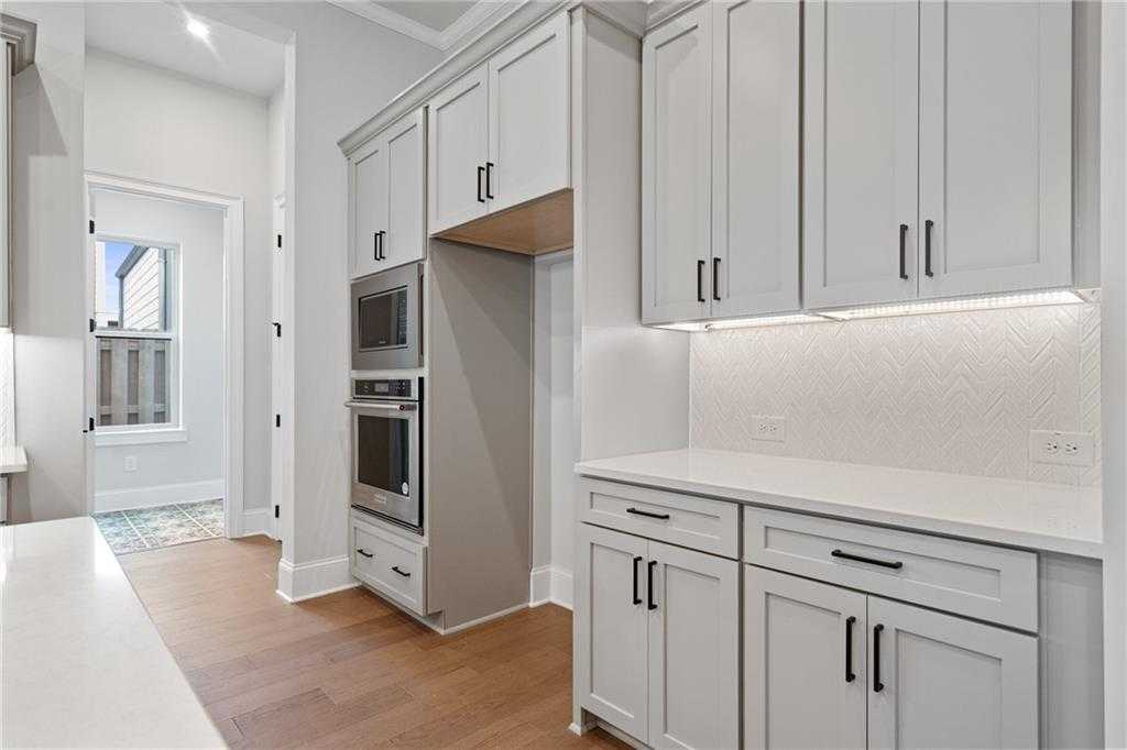 Modern white shaker kitchen with double wall ovens, herringbone tile backsplash, and island in Davidson Homes Seaside B, Woodstock, GA