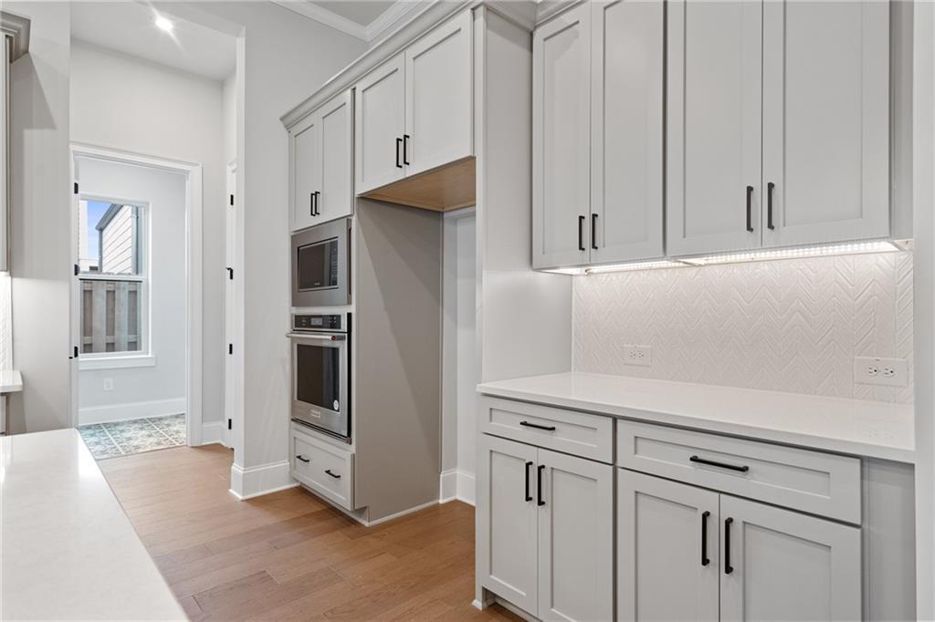 Modern white shaker kitchen with double wall ovens, herringbone tile backsplash, and island in Davidson Homes Seaside B, Woodstock, GA