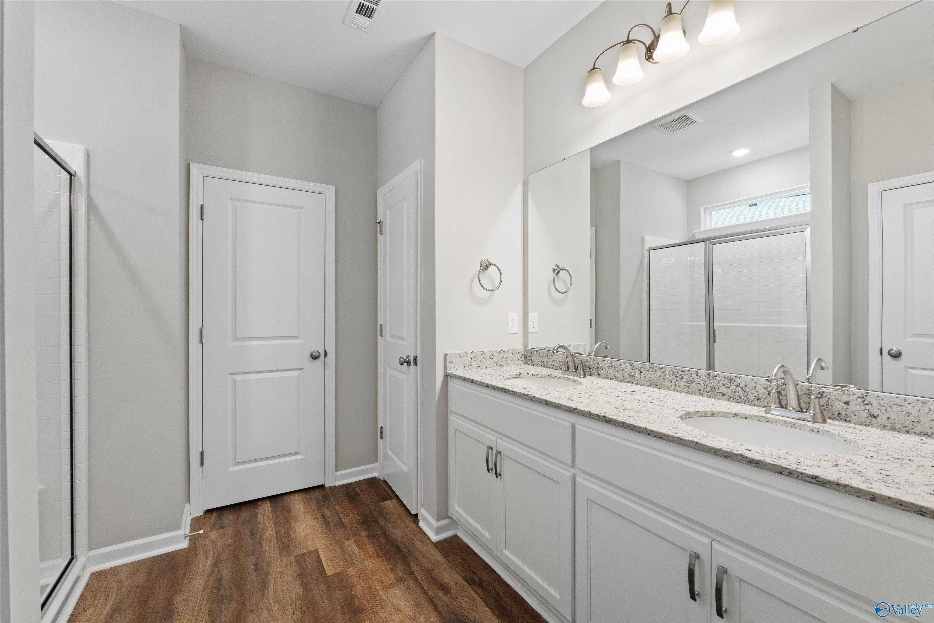 Elegant master bathroom with double vanity, quartz counters, and glass shower in Davidson Homes The Luna, Hazel Green, Alabama