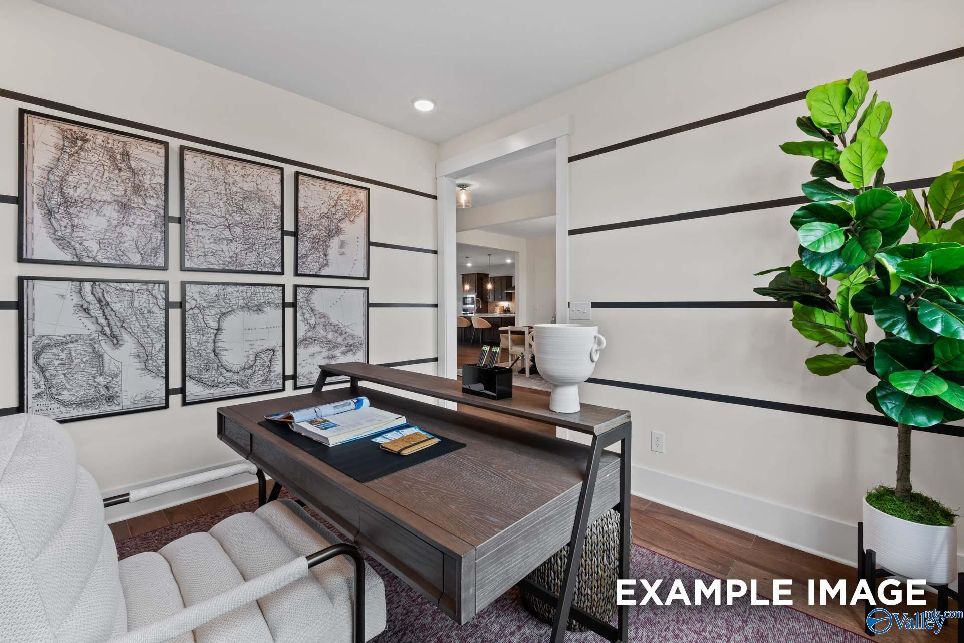 Cozy home office with wooden desk, white chair, fiddle leaf plant and framed world maps in Davidson Homes The Finleigh, Huntsville