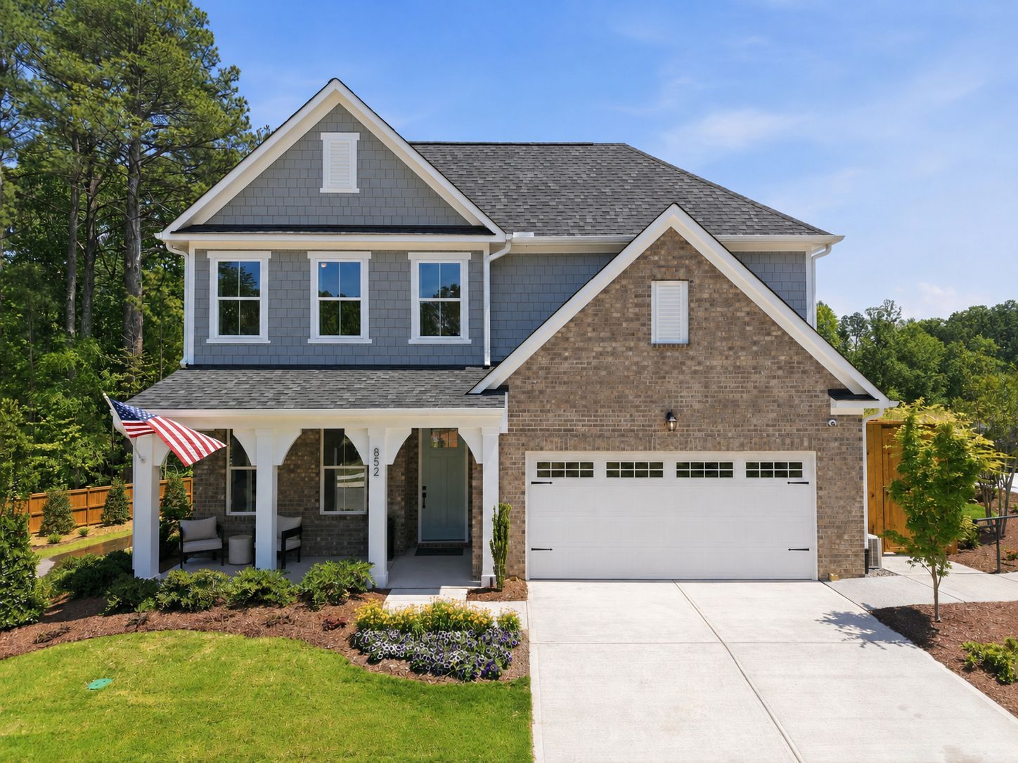 Two-story brick and siding home exterior at Sage on North Main in Wake Forest, NC, featuring a covered porch and garage.