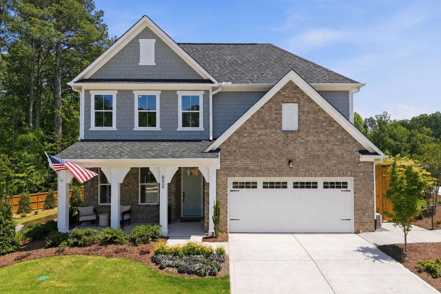 Two-story brick and siding home exterior at Sage on North Main in Wake Forest, NC, featuring a covered porch and garage.