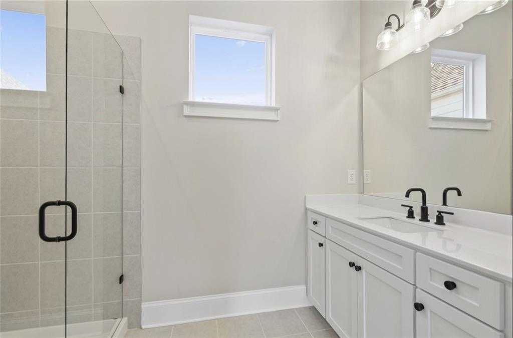 Modern master bathroom with frameless glass shower, double vanity, and white cabinets in Davidson Homes The Seaside A, Woodstock, GA