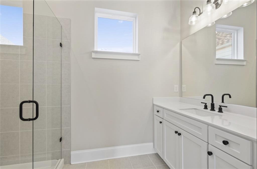 Modern master bathroom with frameless glass shower, double vanity, and white cabinets in Davidson Homes The Seaside A, Woodstock, GA