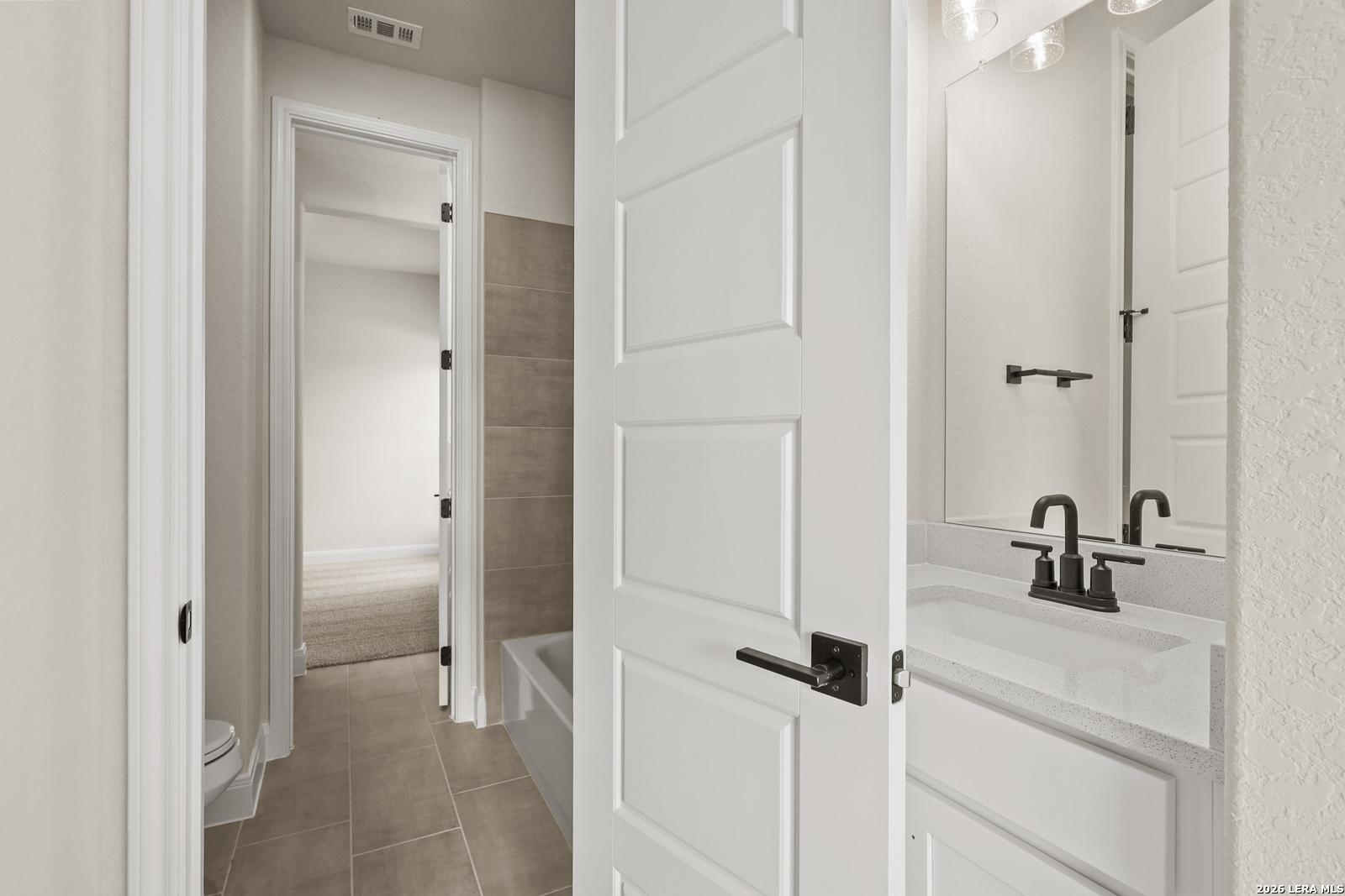 Modern bathroom with white vanity and matte black fixtures in The Summerlin B floor plan by Davidson Homes in Castroville.