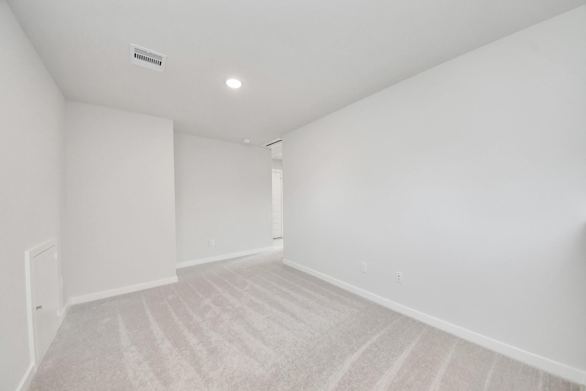 Spacious, carpeted flex room with neutral walls in The Blanco E floor plan at Caney Creek Place, Conroe, Texas.