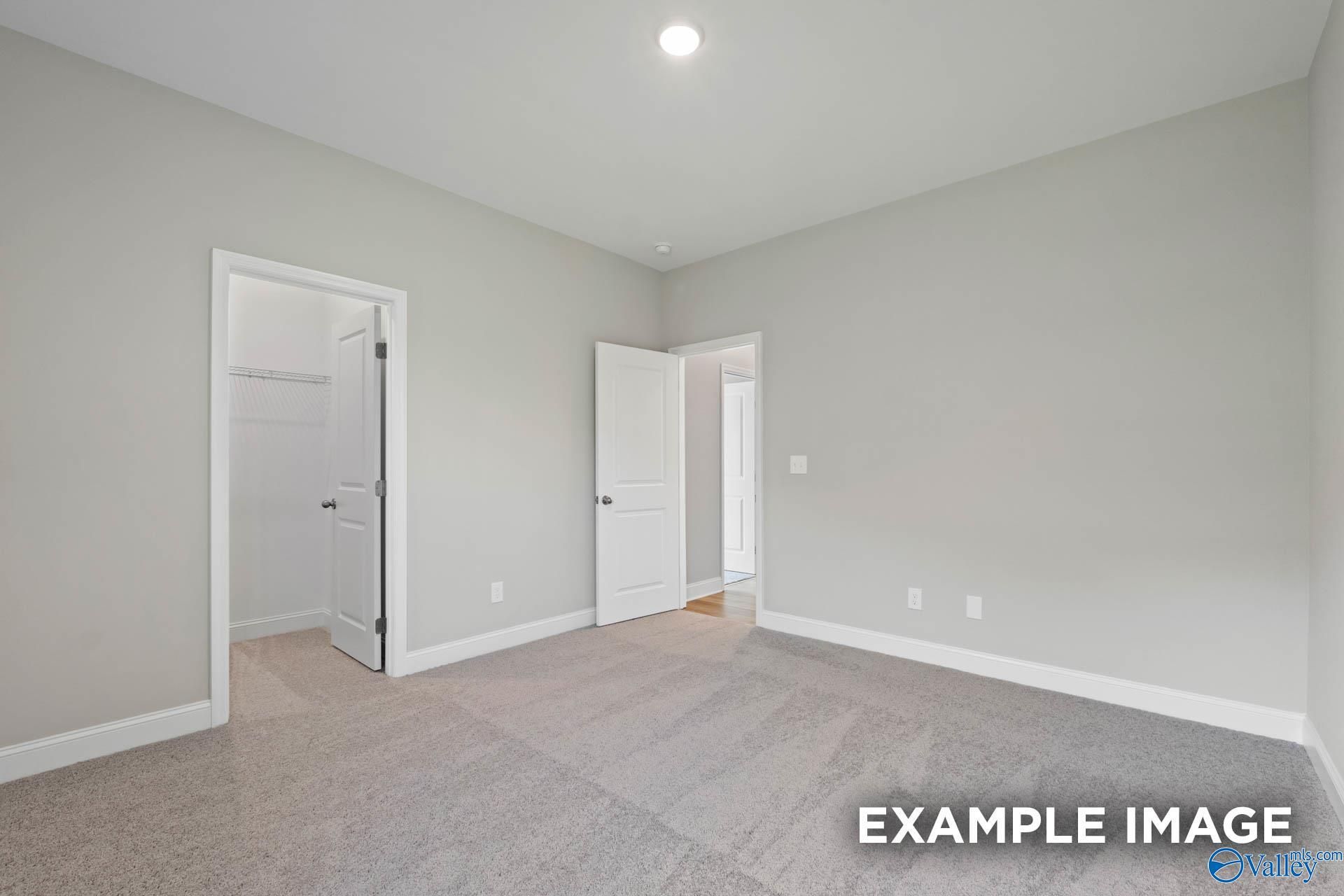 Bright secondary bedroom with gray walls, beige carpet, walk-in closet in The Montgomery B by Davidson Homes, Hartselle, Alabama